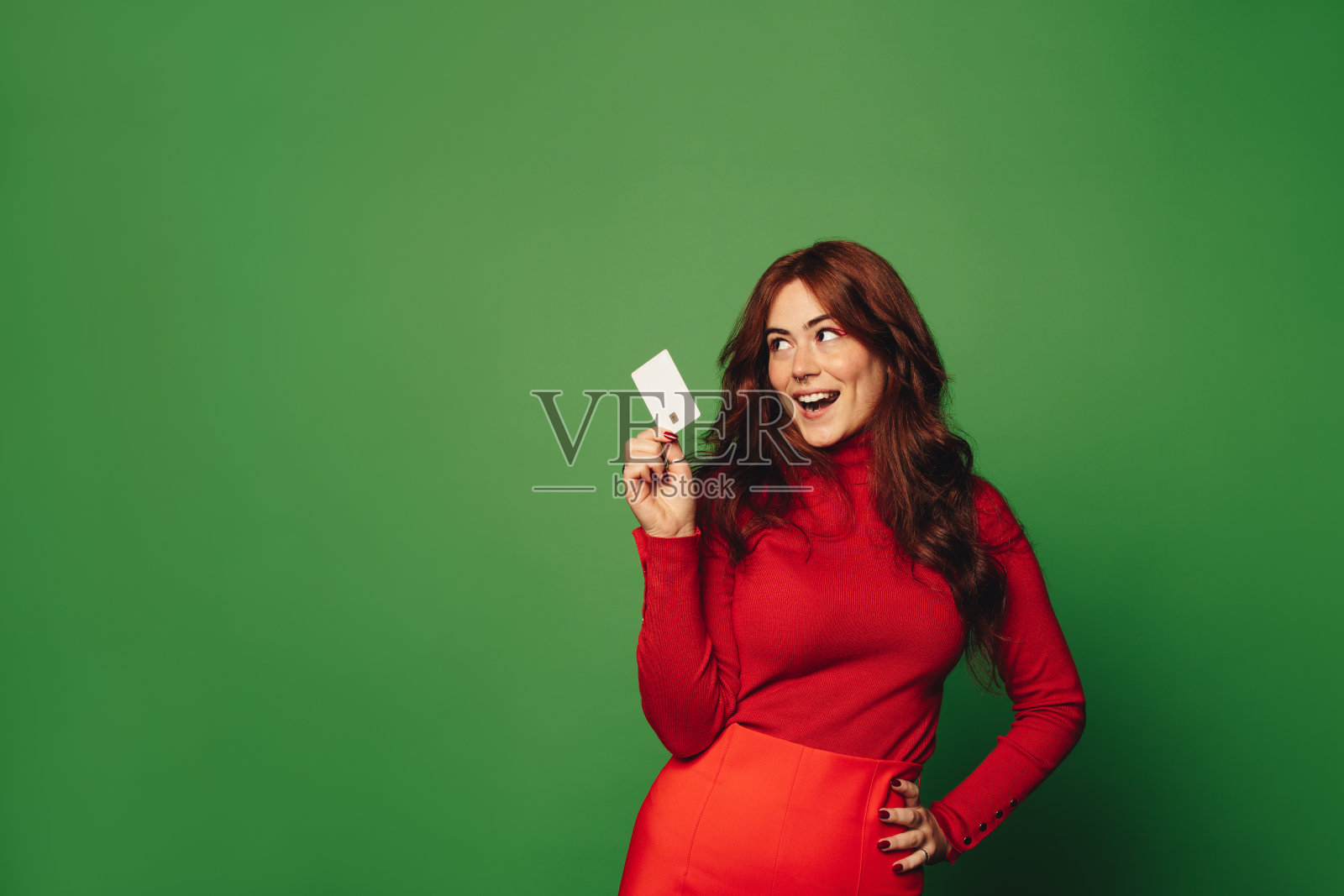 时尚的女人拿着信用卡在绿色的工作室背景下购物照片摄影图片