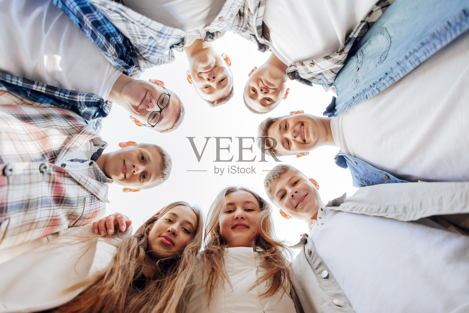 一大群微笑的年轻人站着,拥抱着,看着镜头。一群兴高采烈的青少年围成一圈向下看。低视角。副本的空间。照片摄影图片