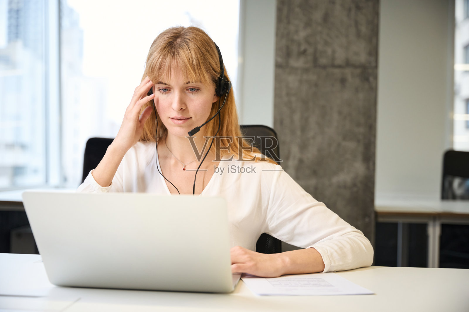 在网上销售中,戴着耳机与客户沟通的忙碌女性照片摄影图片