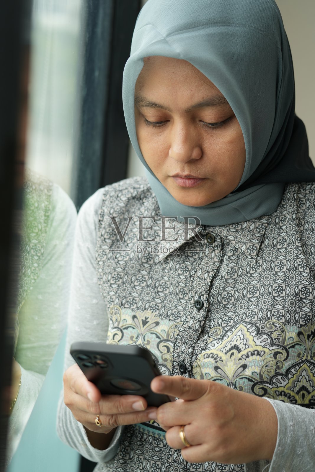 在一家咖啡馆里,一名戴着头巾的妇女拿着手机照片摄影图片