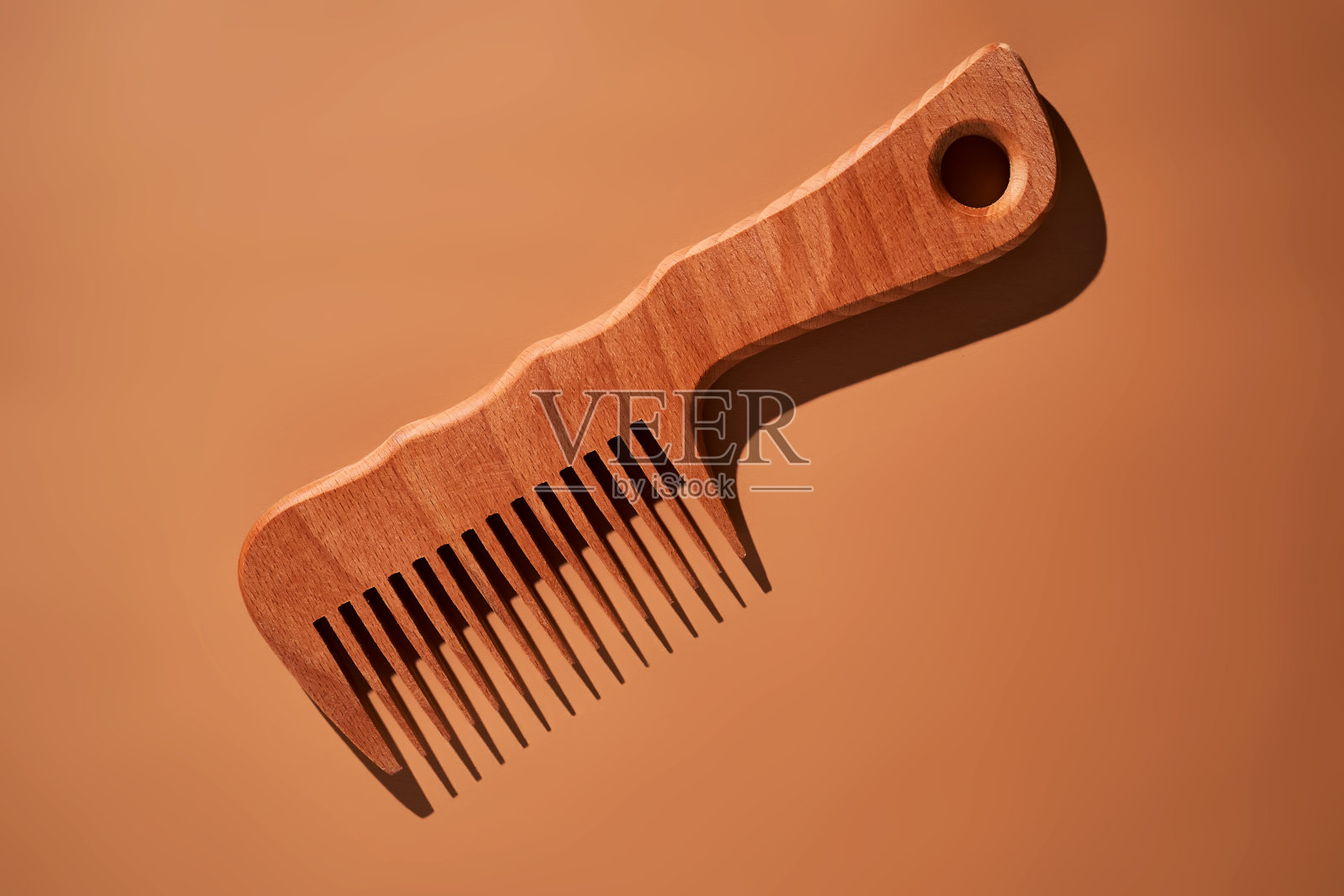米色背景上的木制梳子。照片摄影图片