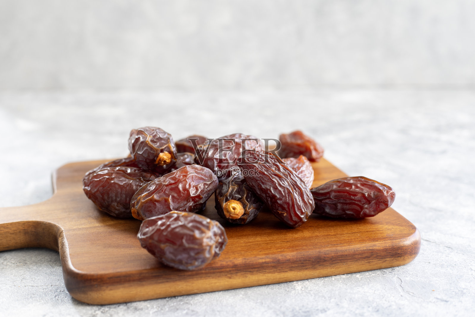 一堆有机的枸杞枣在一个木制的餐板上。斋月的食物。照片摄影图片