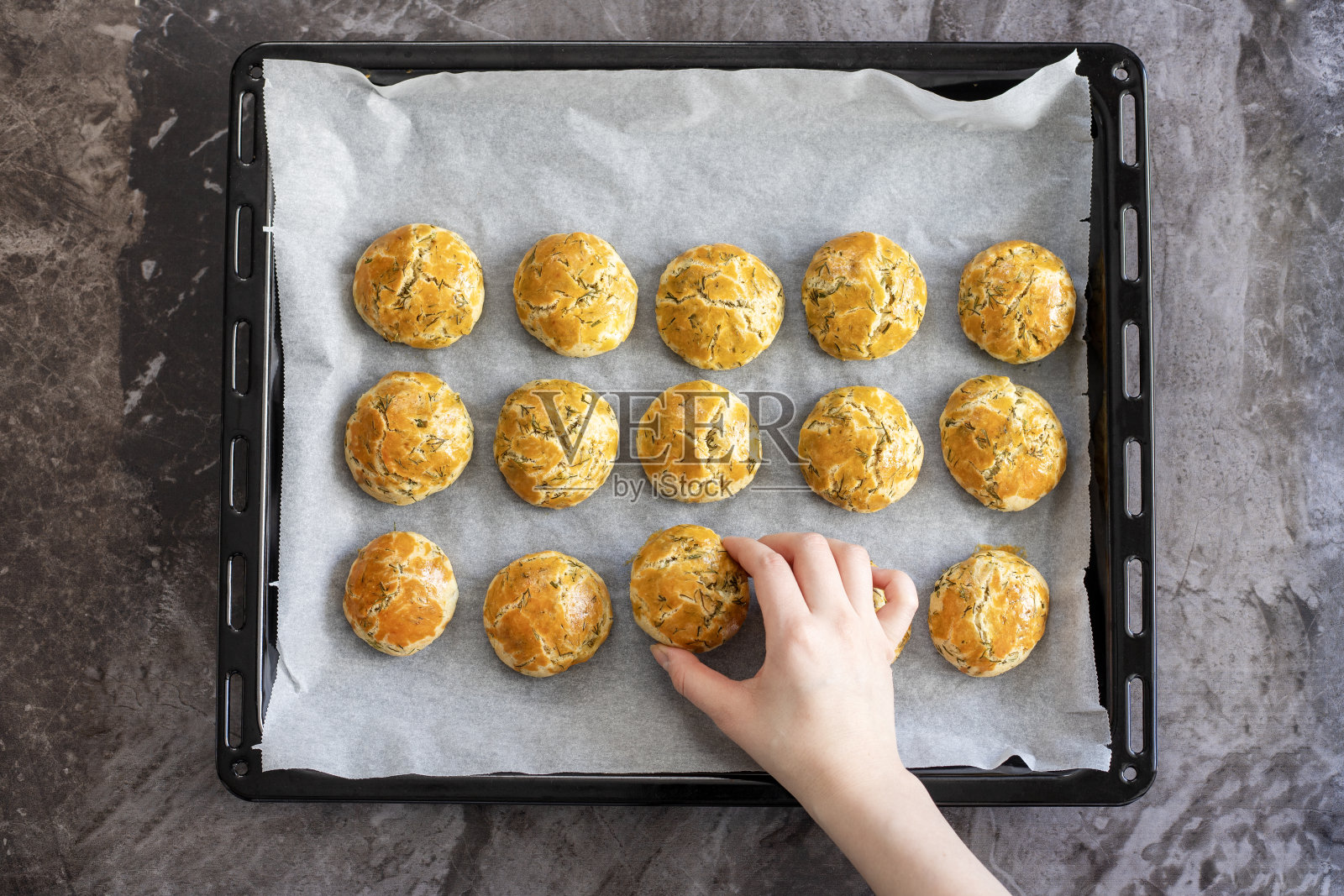一位女士从烤盘中取出刚烤好的马铃薯照片摄影图片