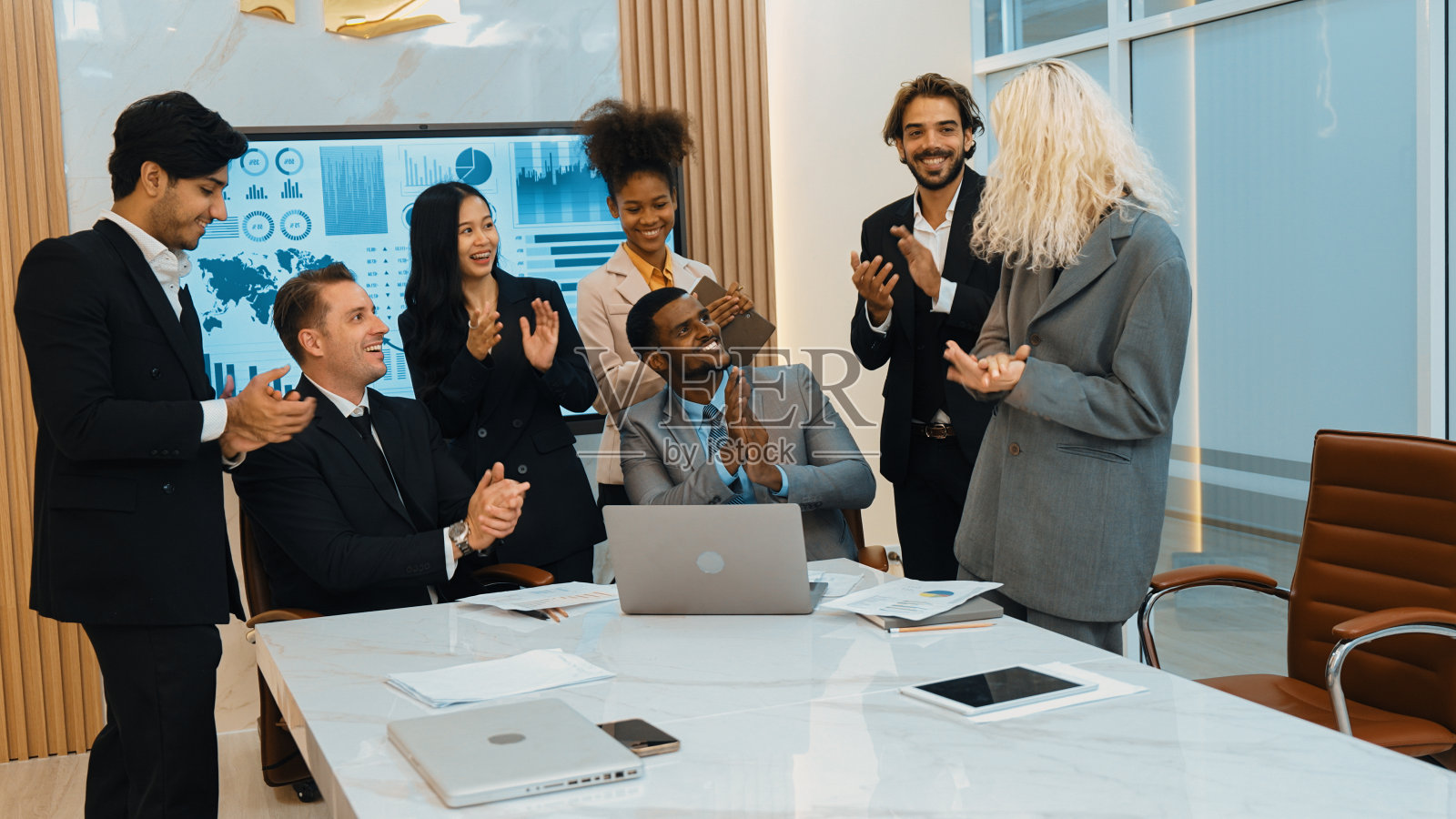 在装饰华丽的办公室里,各种各样的上班族和员工在鼓掌。照片摄影图片