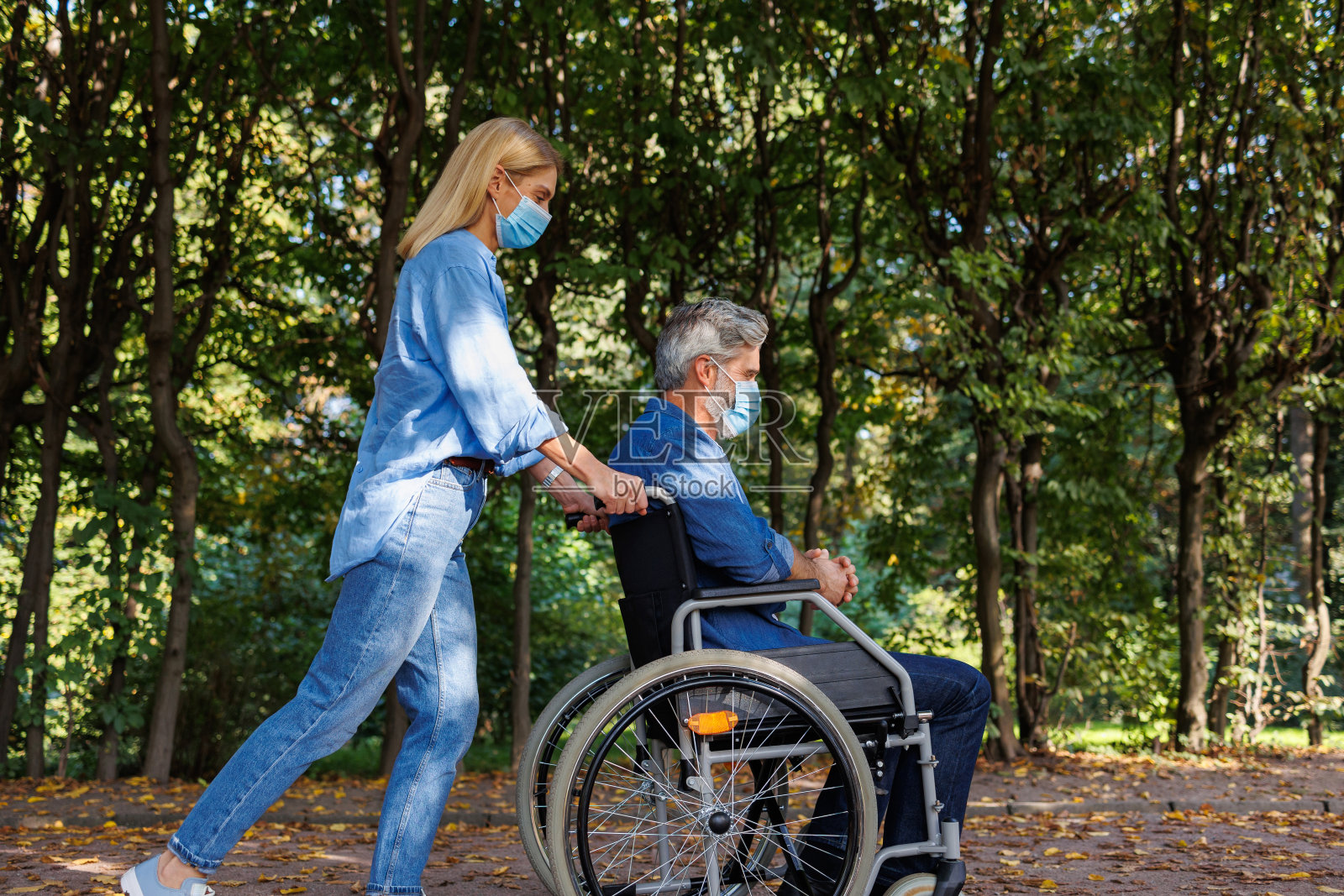 社区护理:轮椅上的男女在公园环境中戴口罩照片摄影图片