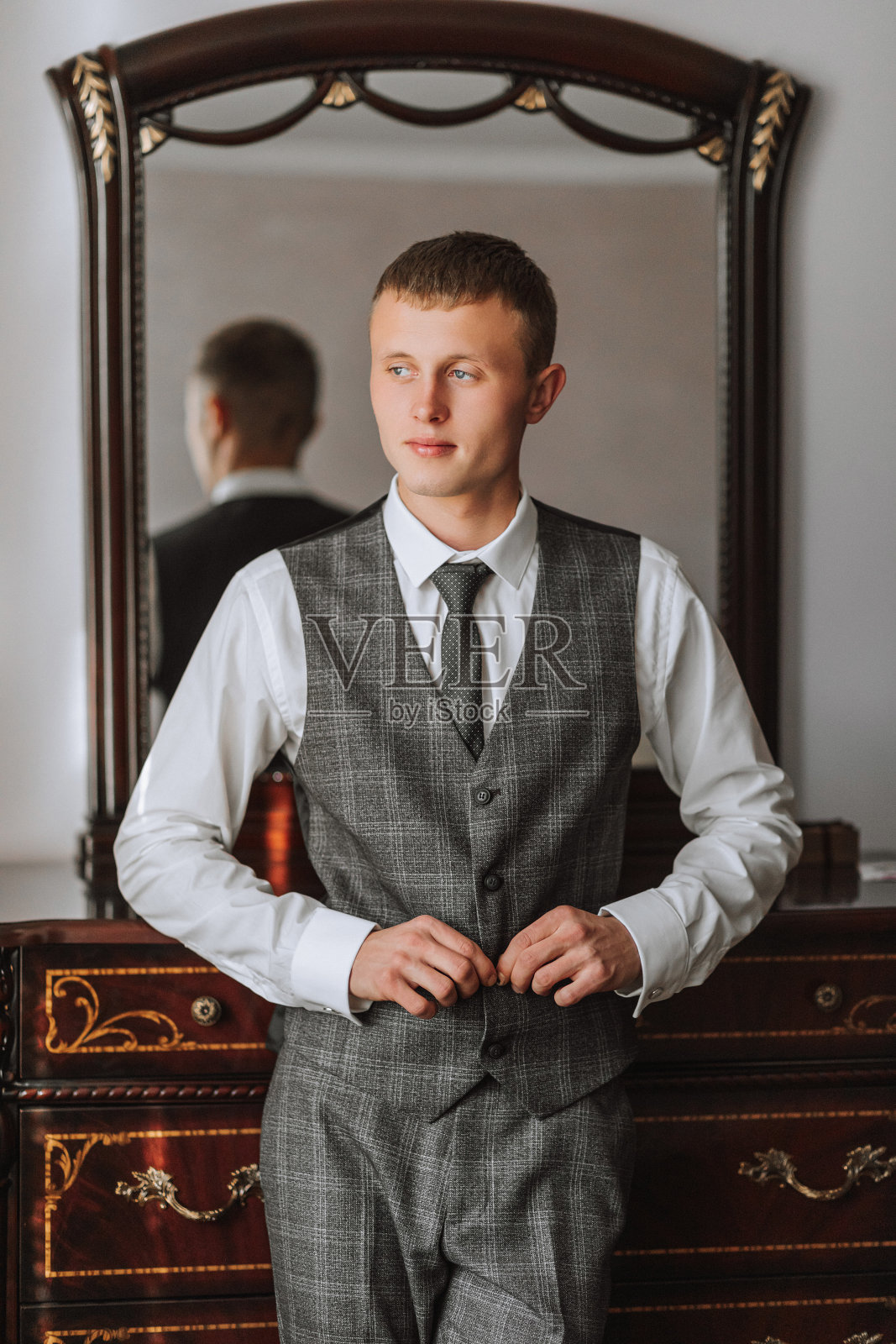 一个时髦的年轻人穿着西装打着领带。商务风格。时尚的形象。新郎正在为婚礼做准备。性感男人站起来,看向别处照片摄影图片