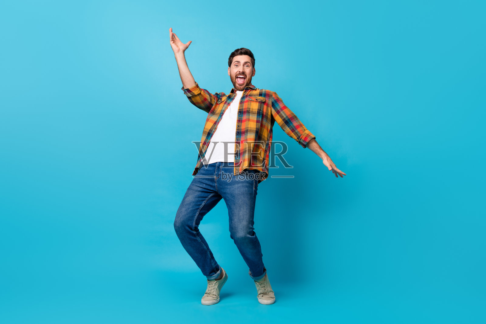 有魅力的年轻人穿着时尚的格子衣服在蓝色背景上跳舞庆祝节日的全身照片照片摄影图片