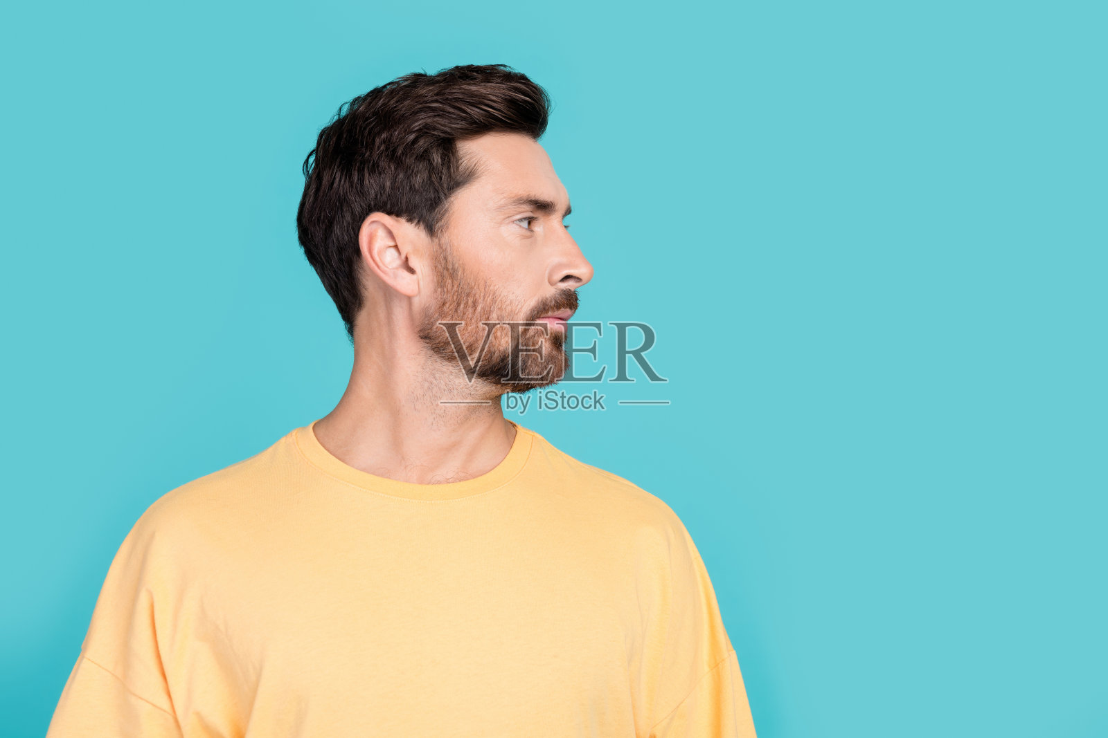 个人资料照片,严肃自信的男人穿着黄色时髦的t恤,看起来发型类型的选择孤立的海蓝宝石色背景照片摄影图片
