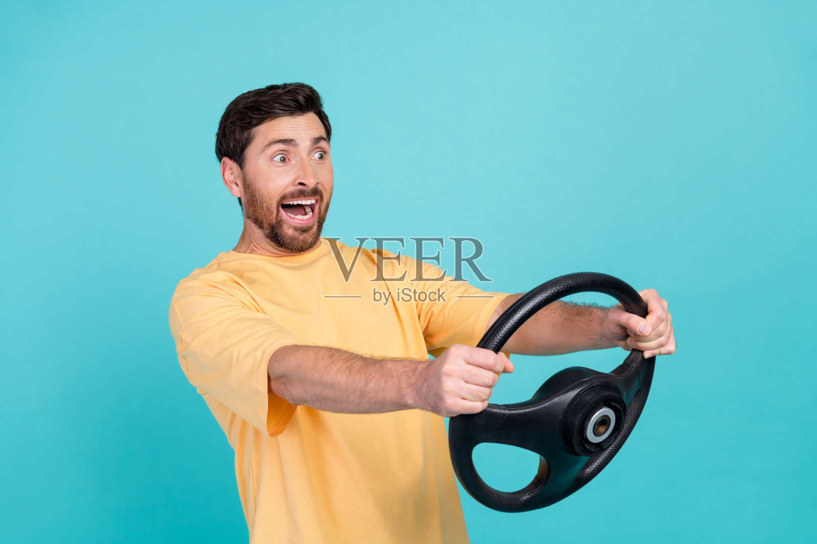 年轻男子出租车司机在事故发生前骑得太快,在青色背景上拿着方向盘照片摄影图片