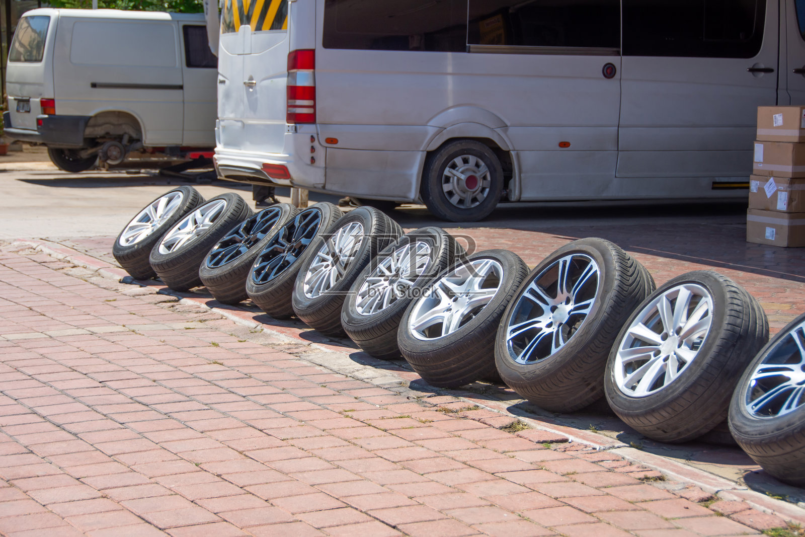 一排排的各种轮辋用橡胶轮胎陈列着,旁边的车库有一辆轮毂更换服务的小巴面包车。照片摄影图片