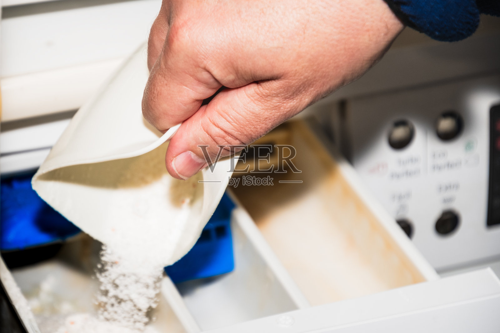 男子用手把肥皂倒进洗衣机的抽屉里照片摄影图片