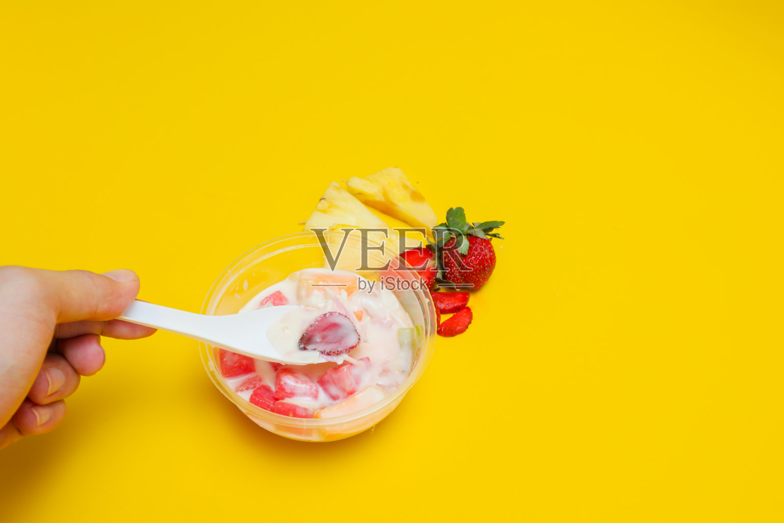 Es buah或sup buah是印度尼西亚的水果鸡尾酒冰甜点,含有草莓、菠萝和其他热带水果,与冰块和炼乳混合。孤立在黄色背景。照片摄影图片