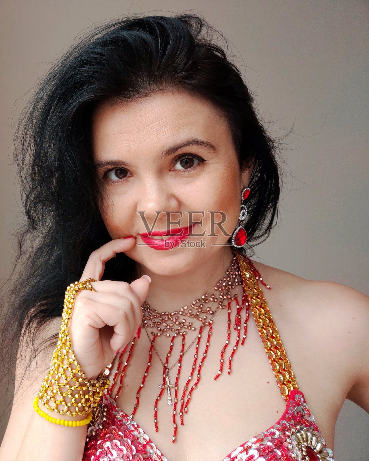 一位身穿红色衣服的舞者正在白色背景上跳东方舞。一位专业舞者跳东方肚皮舞。穿着红裙子的性感女人在白色的工作室里跳着诱人的舞蹈。隔离。专业舞蹈教练。东方人服装照片摄影图片