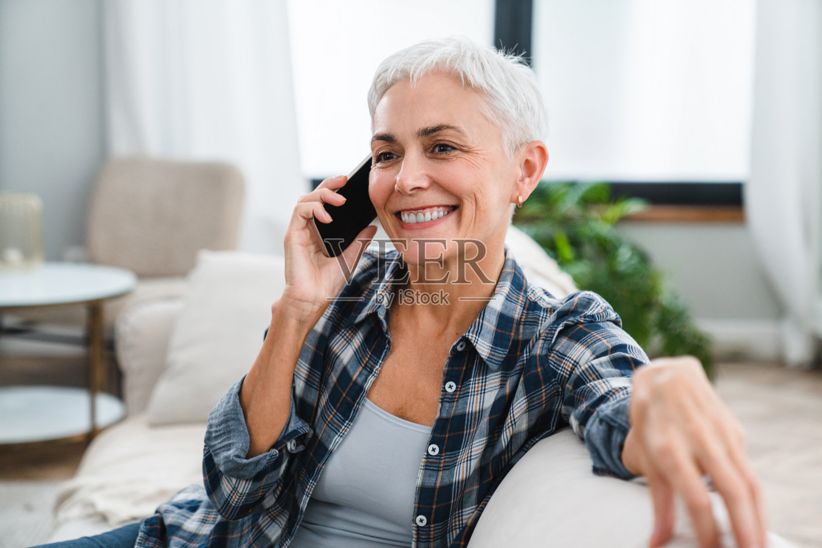 在家中用手机与客户在线交谈的快乐中年妇女照片摄影图片