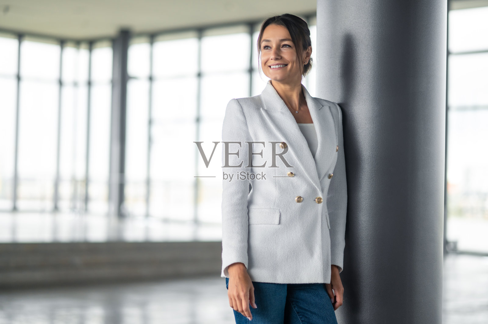 站在柱子旁边的漂亮微笑的女商人照片摄影图片