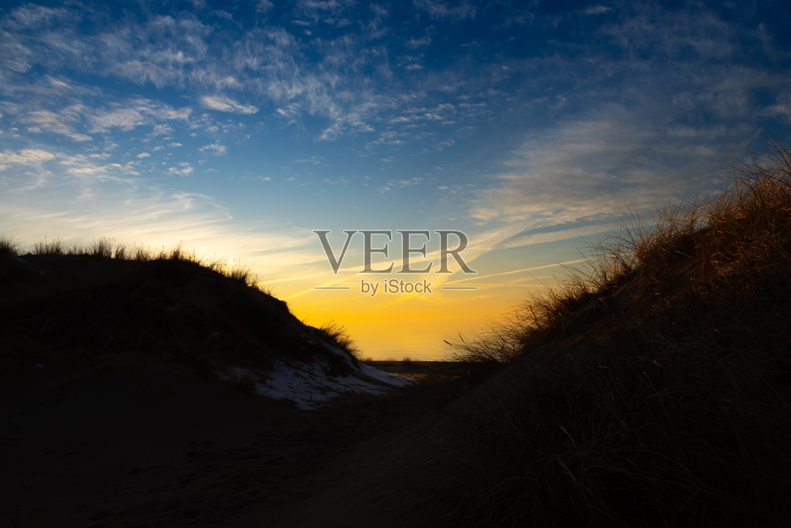 美丽的早春景色,波罗的海海滩,草地的剪影映衬着色彩斑斓的天空。照片摄影图片