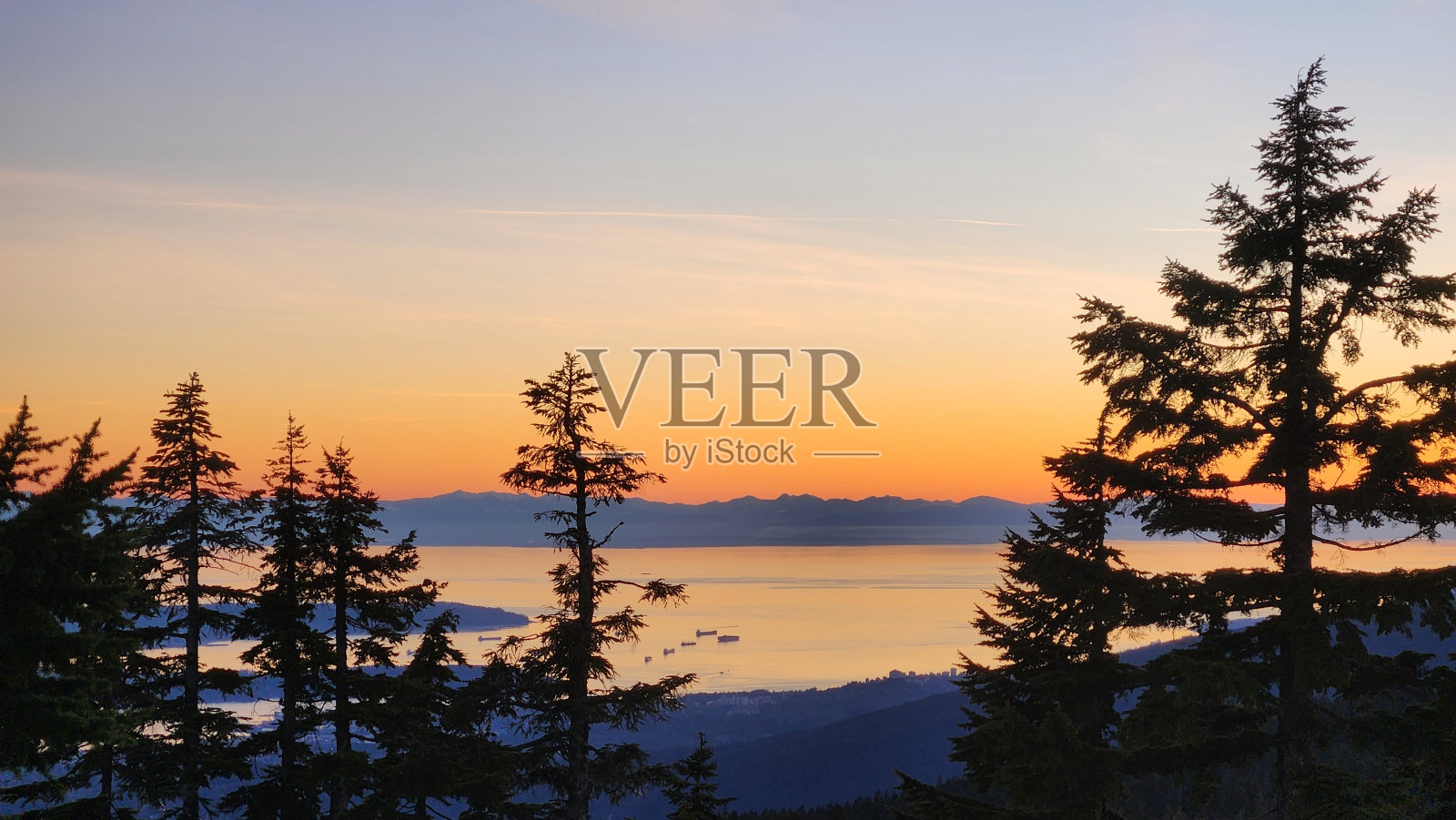 日落时分,山、树、集装箱船的剪影和美丽的黄昏照片摄影图片