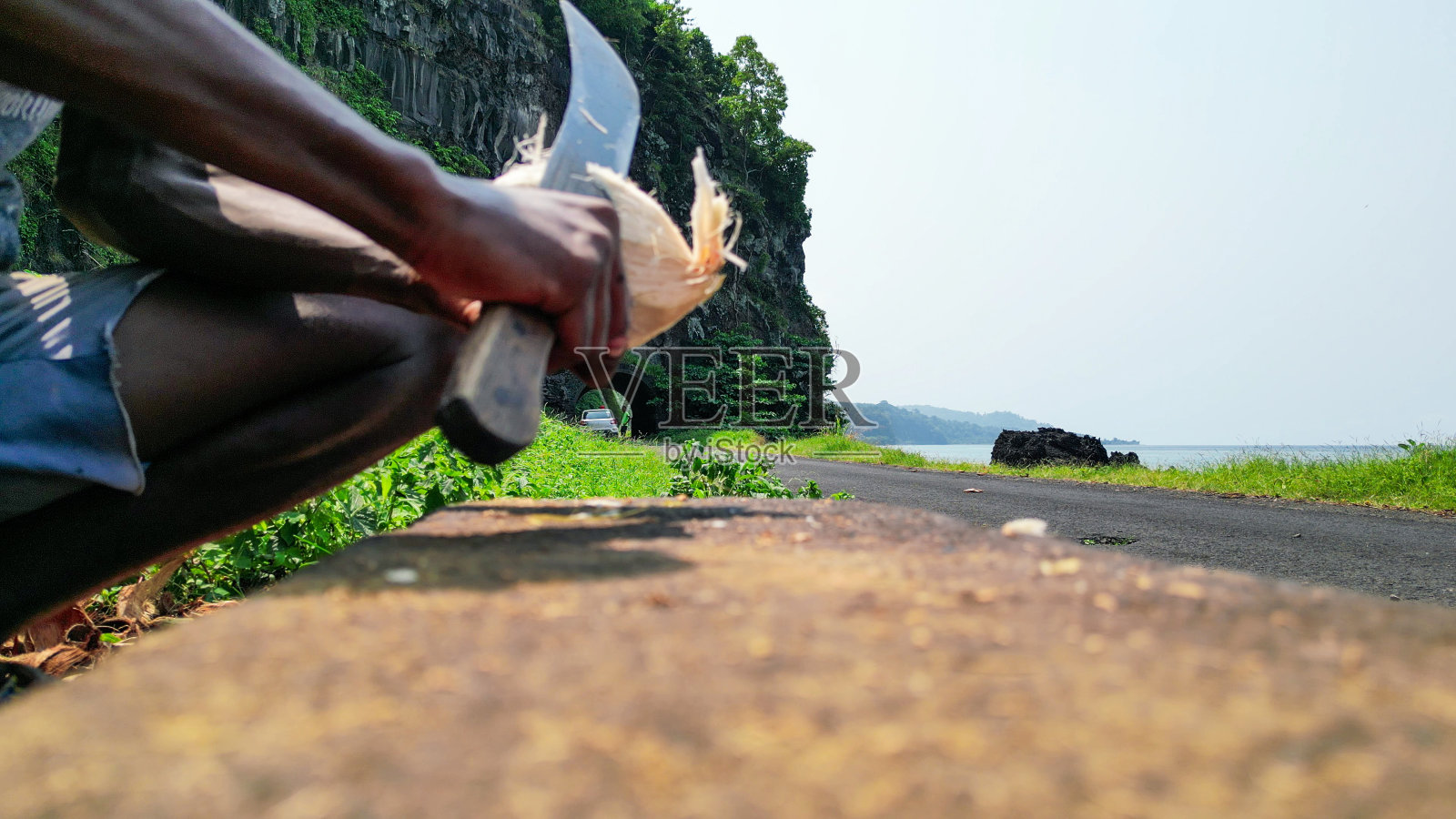 一个非洲人在切椰子,照片摄影图片
