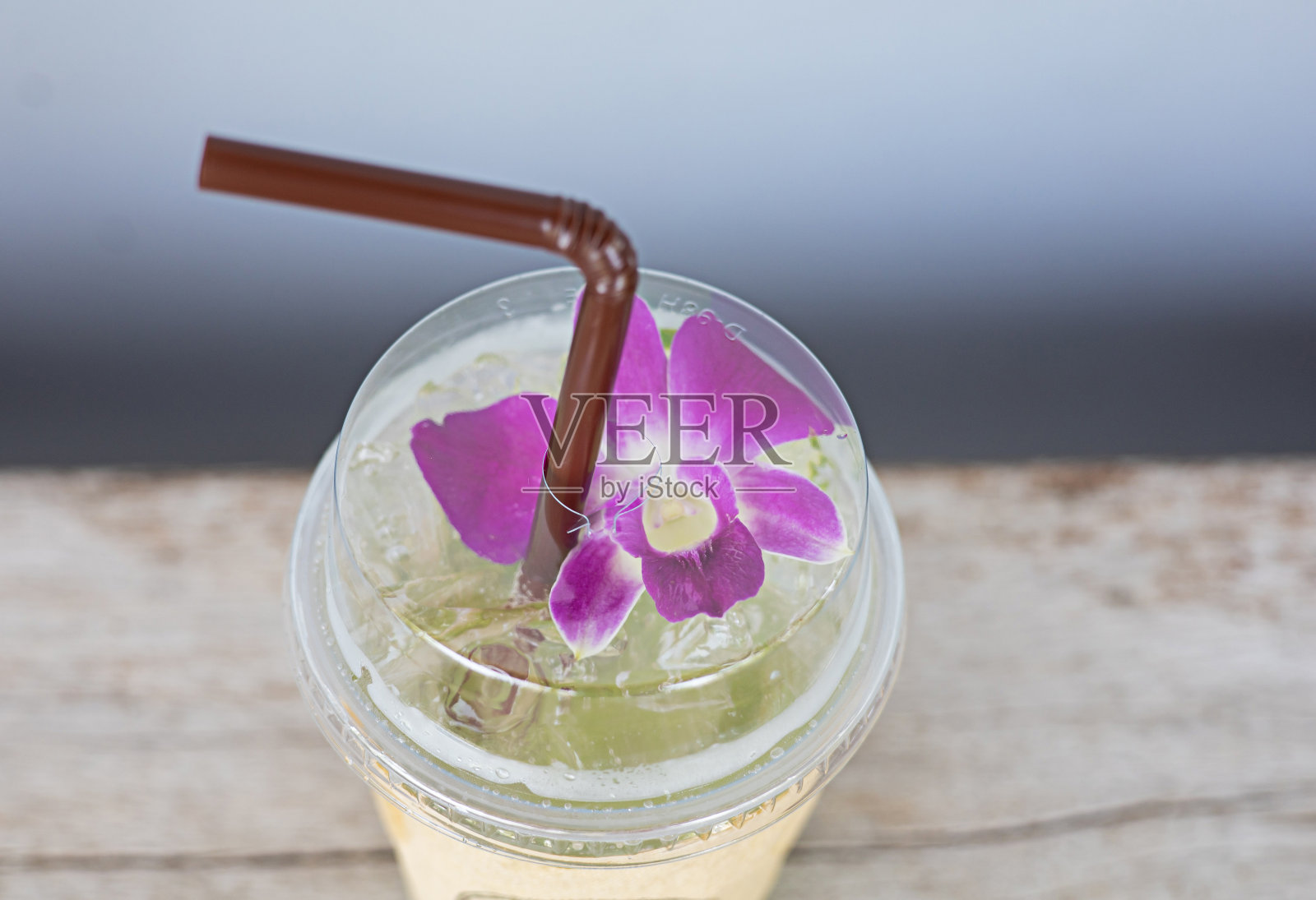 饮料装在塑料玻璃杯里,照片上的角落里装饰着鲜花。照片摄影图片