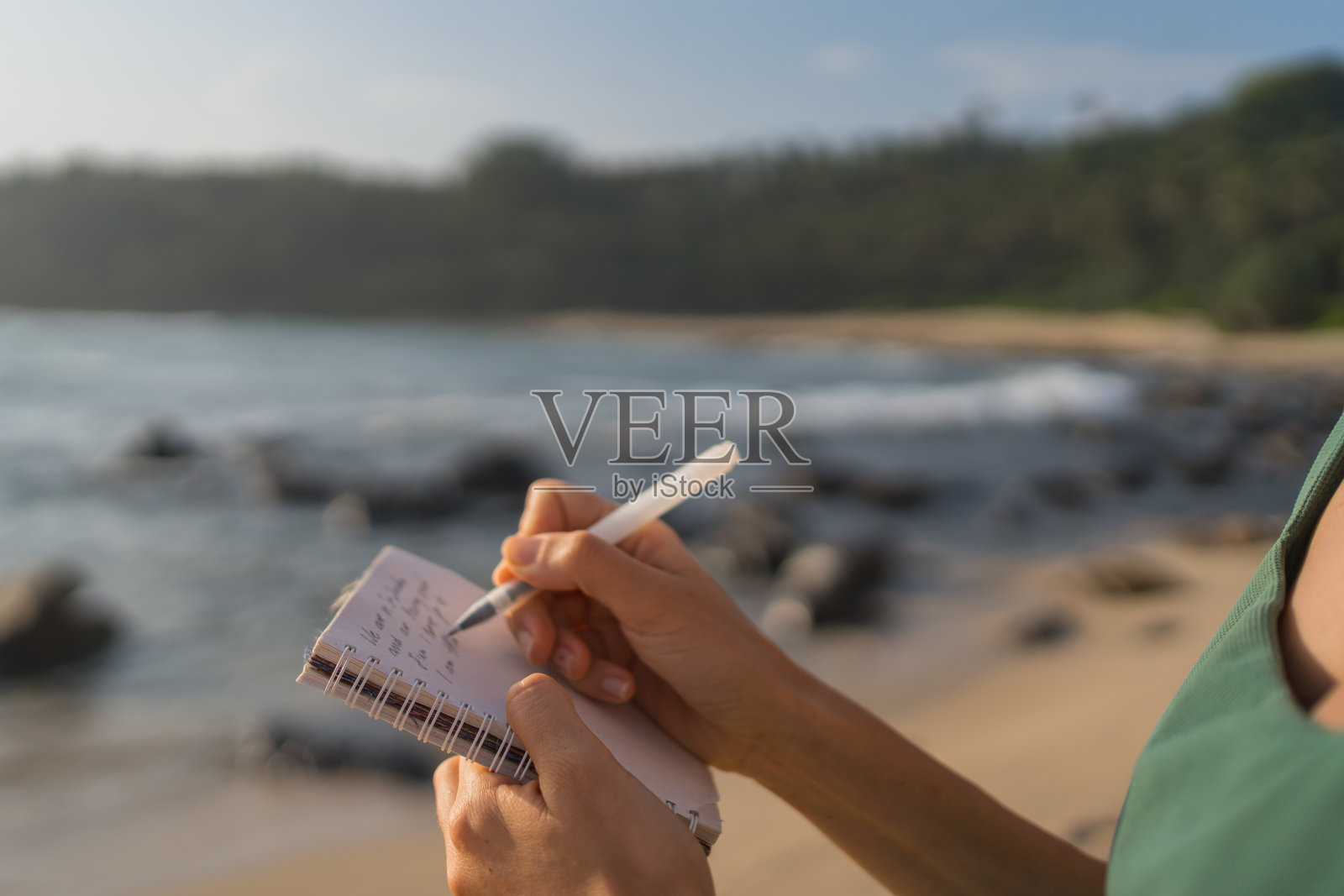 年轻女子在海滩上用记事本写字照片摄影图片