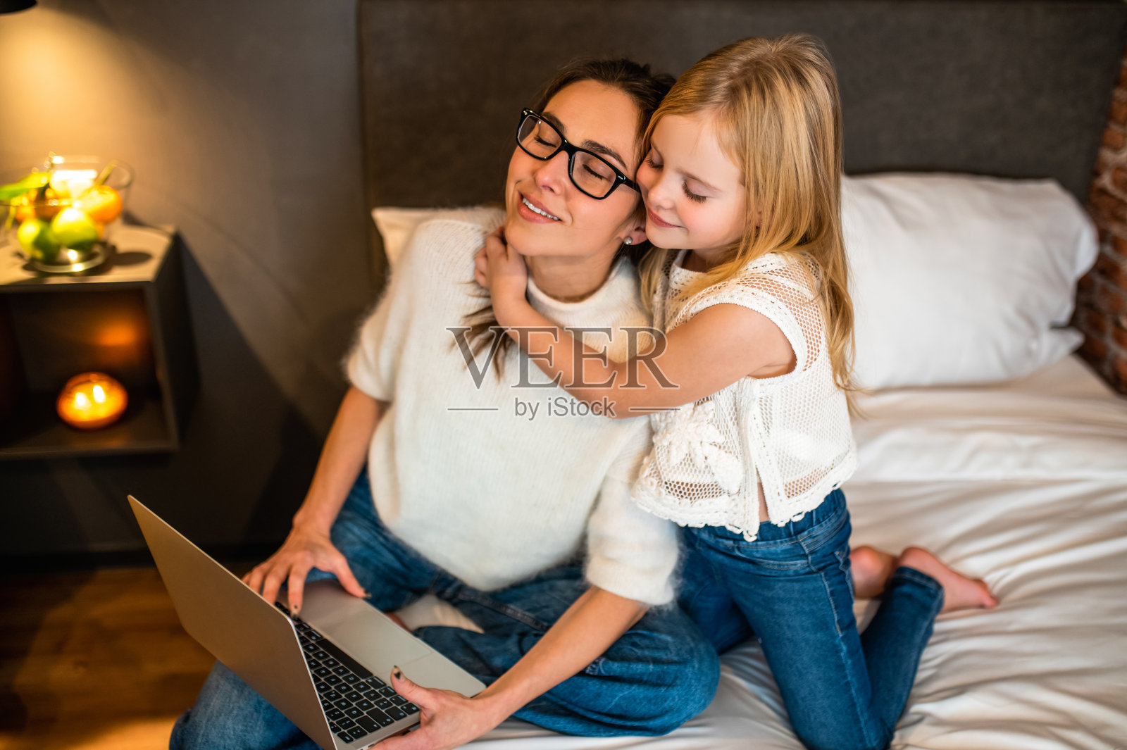 母亲和小女儿在酒店房间用笔记本电脑上网照片摄影图片