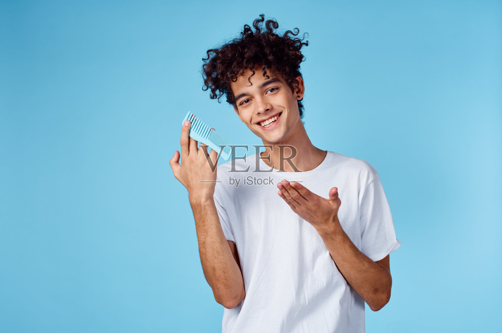 棕色头发,蓝色背景上有一头卷发,手里拿着一把梳子照片摄影图片