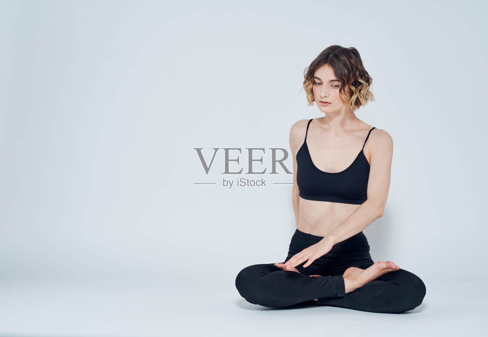 一个穿着打底裤的女人盘腿坐在地板上,转身向两侧照片摄影图片