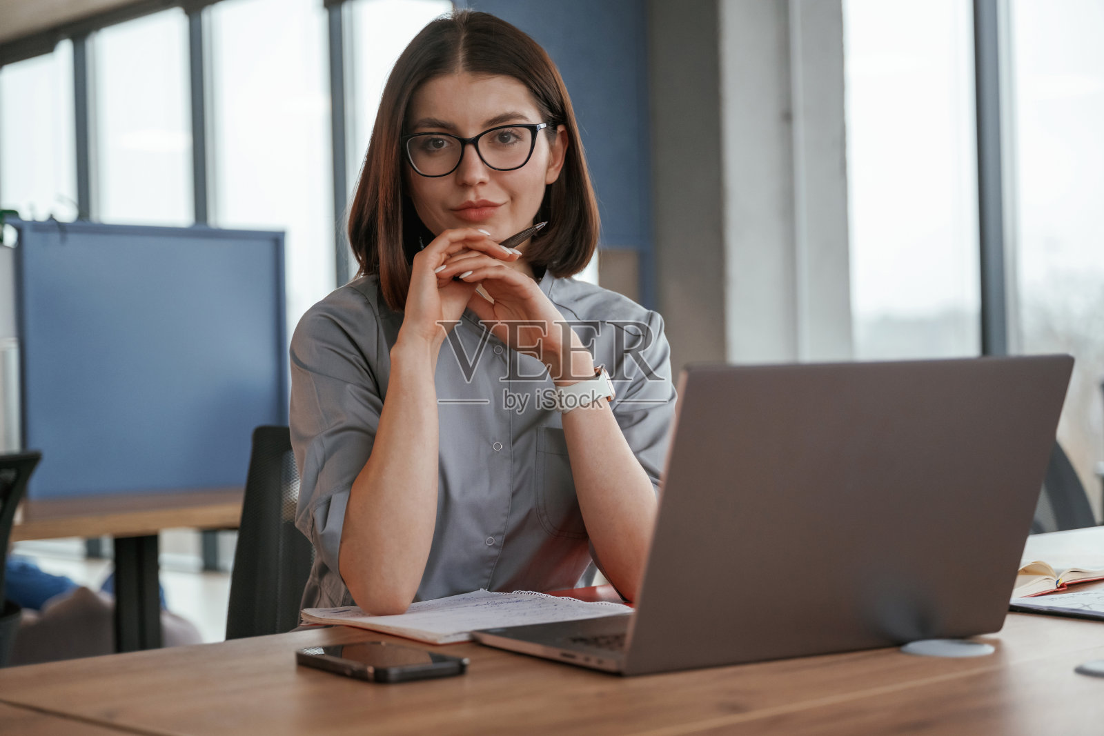 在桌上的笔记本电脑旁。穿大衣的女医生在室内照片摄影图片