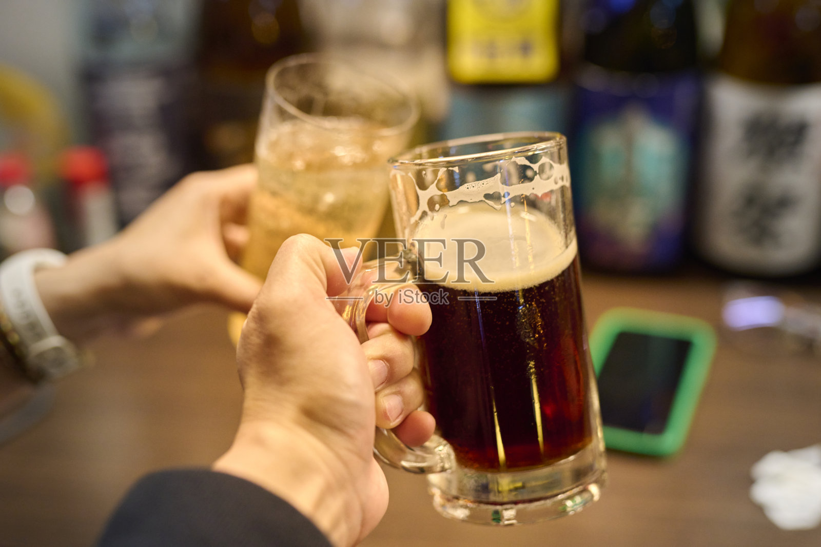 朋友们在日本酒吧餐厅喝啤酒。朋友快乐的概念,年轻人在凉爽的复古酒吧一起玩乐。照片摄影图片