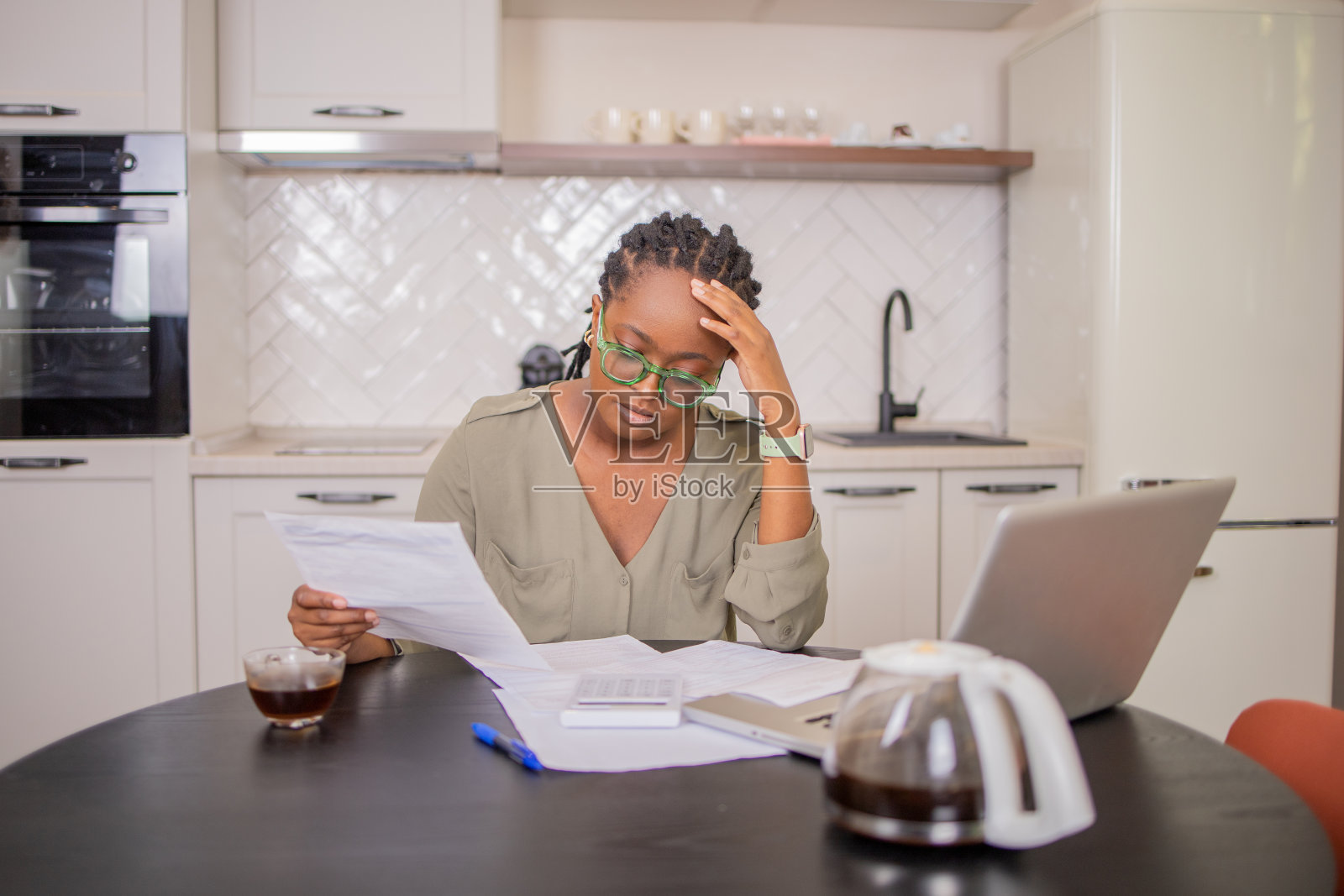 年轻女子使用计算器,同时通过账单和家庭财务照片摄影图片