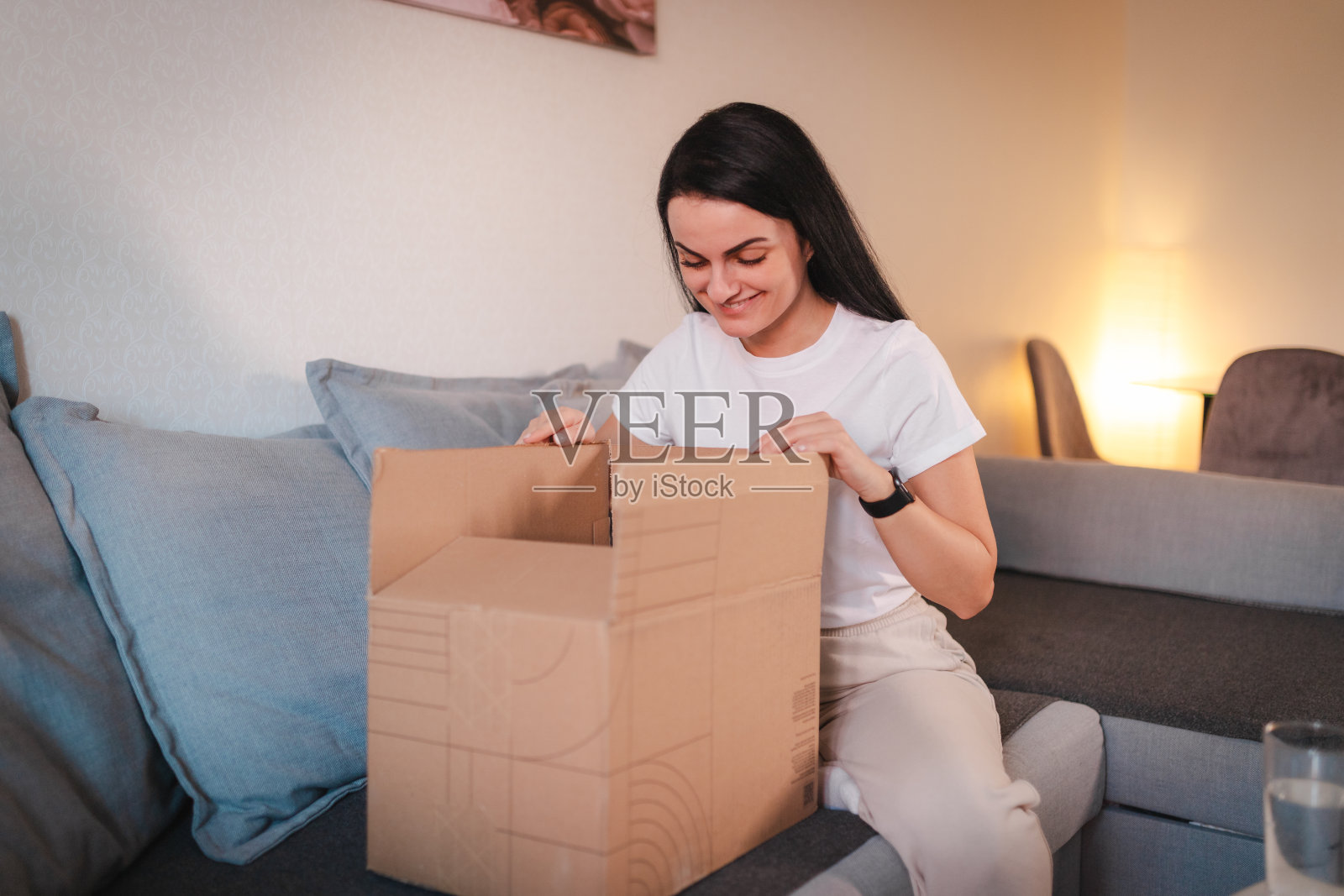 年轻女子打开她在网上订购的包裹照片摄影图片