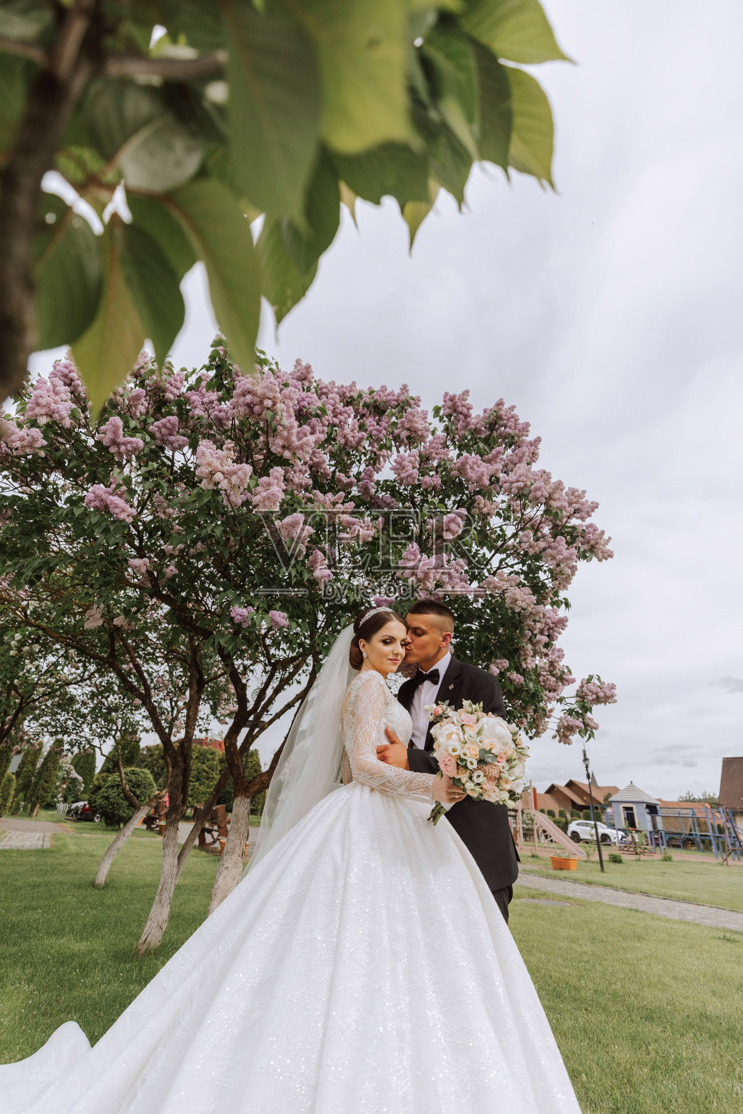 的婚礼。爱与新人在花园举行婚礼。庆祝仪式和承诺。保存日期。信任。新娘和新郎在春天盛开的树的背景下拥抱。照片摄影图片