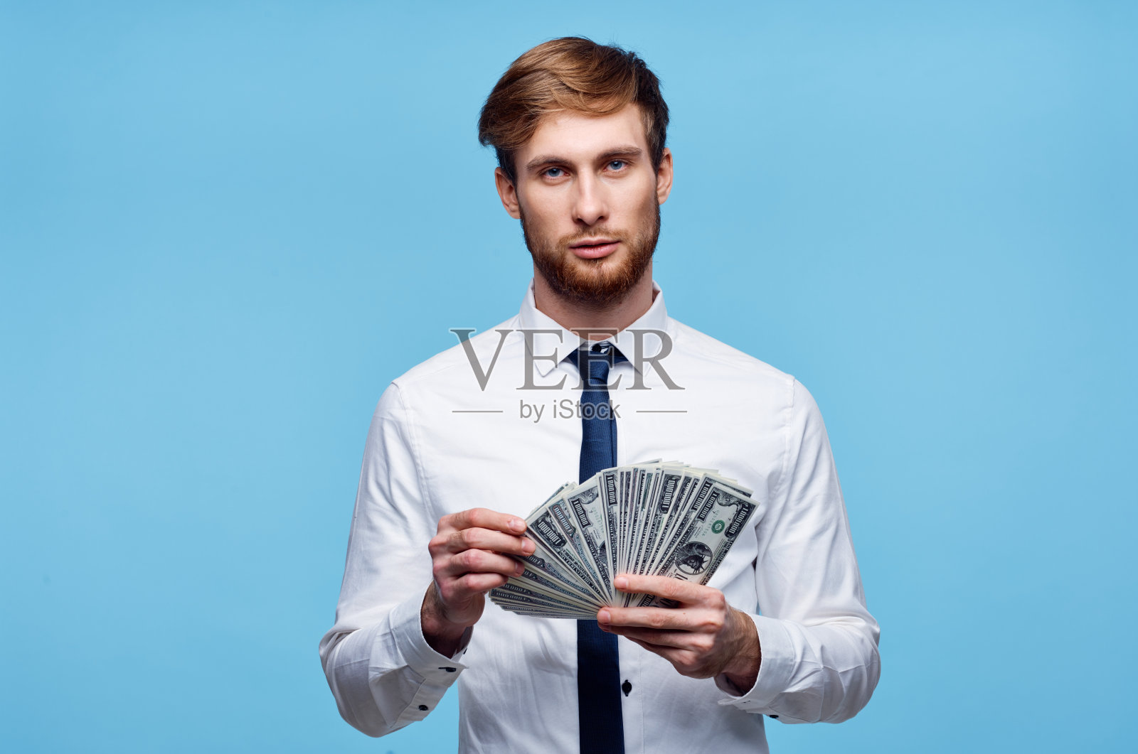 一个商人,穿着衬衫,打着领带,手里拿着一捆钱照片摄影图片