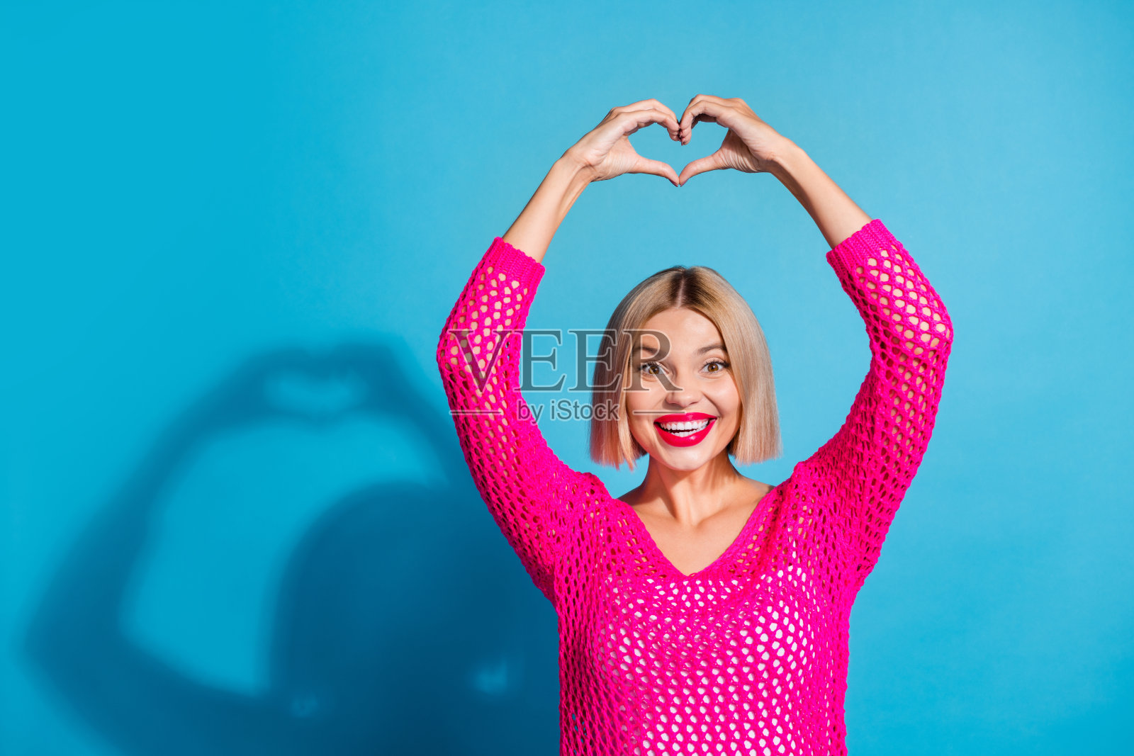 照片中,欢快可爱的妖艳女郎穿着鲜艳的衣服,在蓝色的背景上显示出你内心的身影照片摄影图片