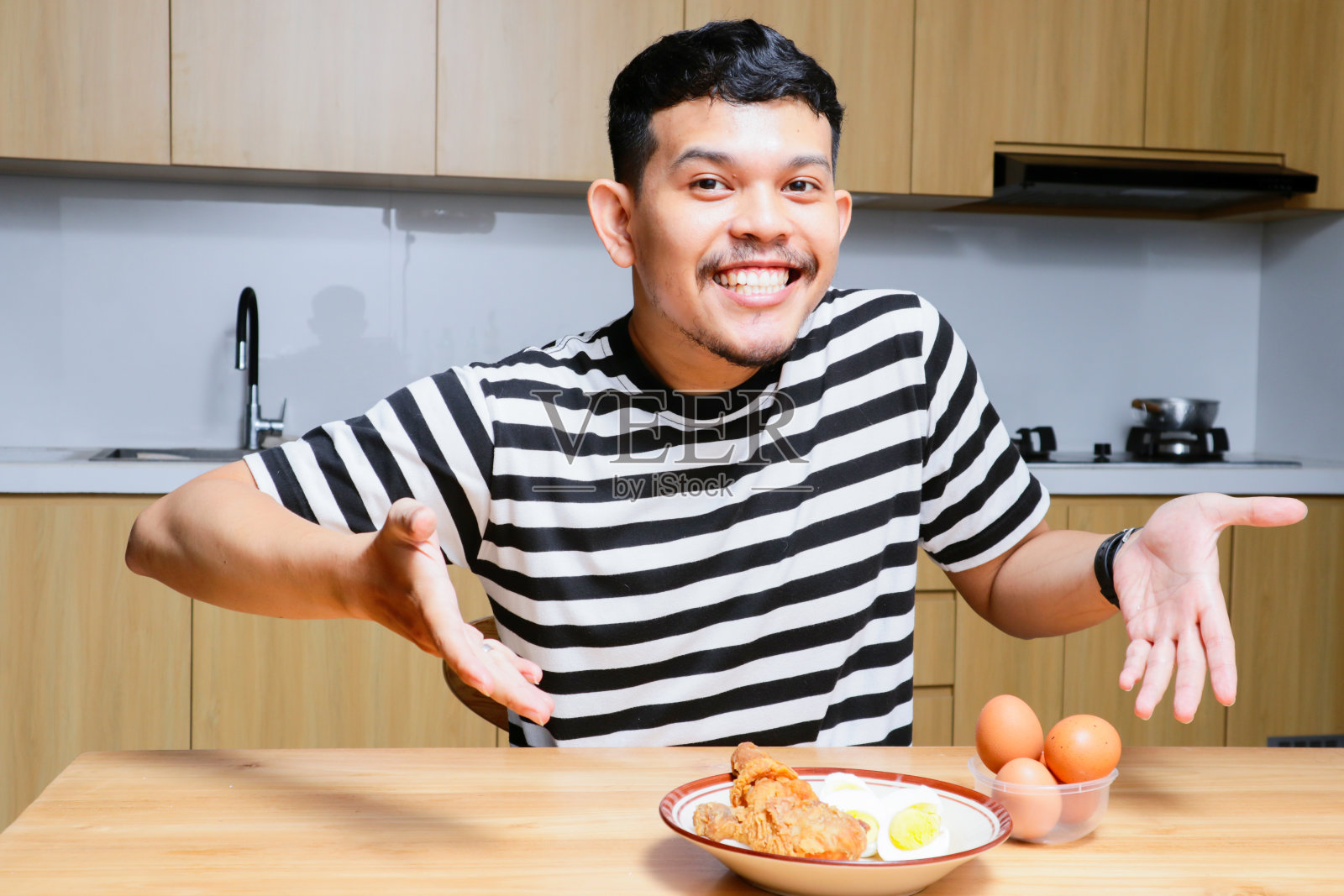 有趣的亚洲人在厨房吃炸鸡和鸡蛋照片摄影图片