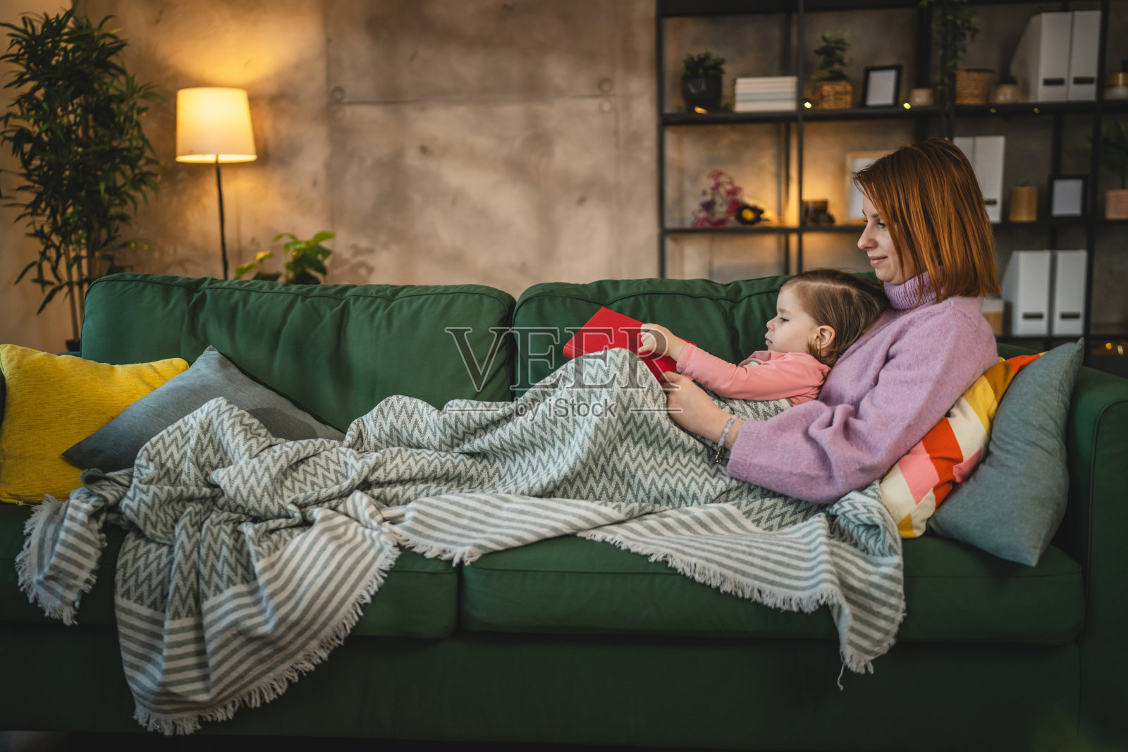 母女俩蹒跚学步的小女孩在家看书照片摄影图片