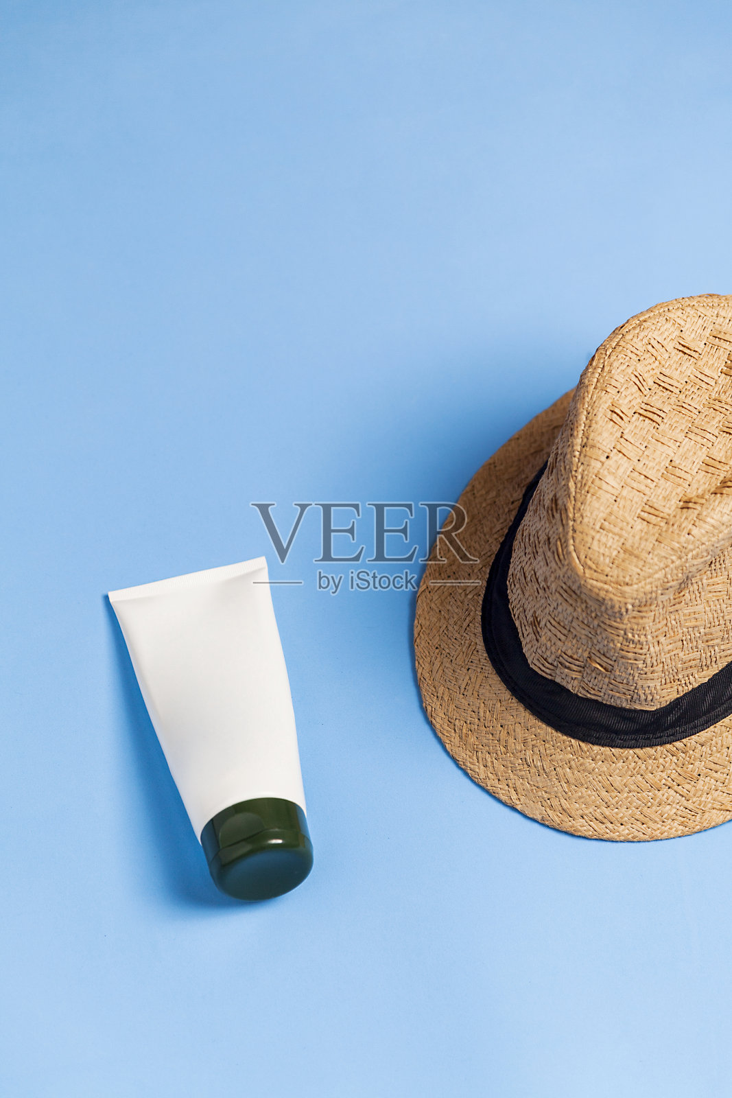 草帽和一瓶防晒霜在蓝色背景照片摄影图片