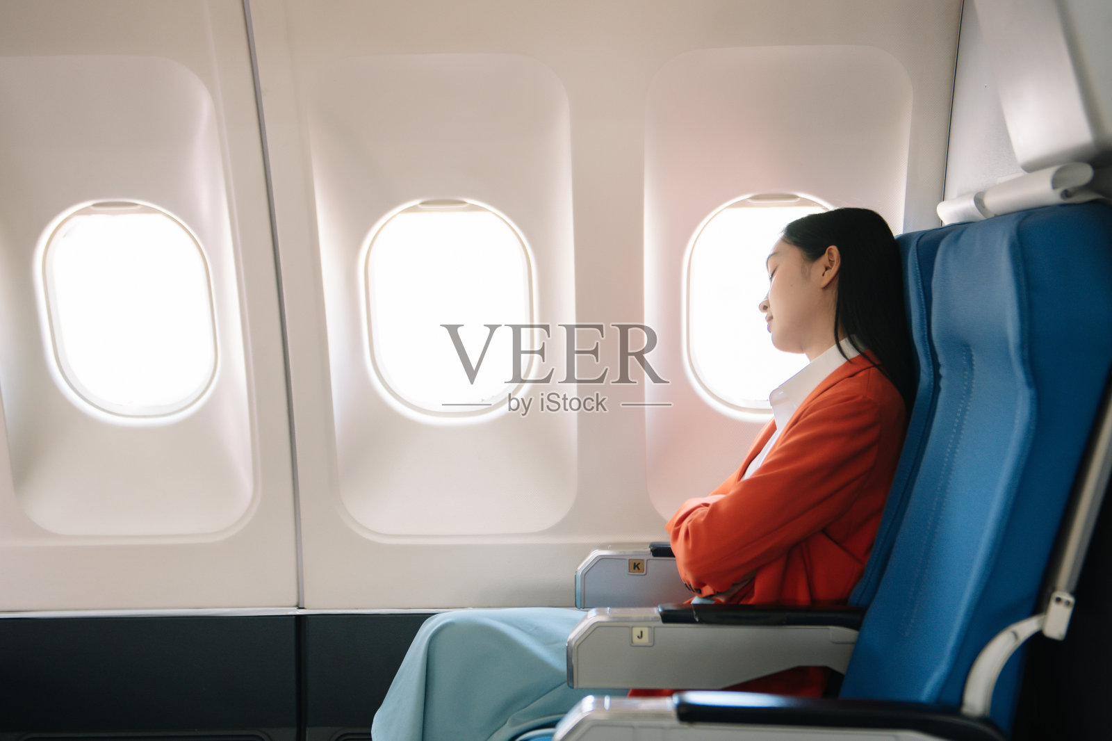 一位沮丧的女士坐在飞机上,双手抱头的照片。一位亚洲女士坐在座位上照片摄影图片