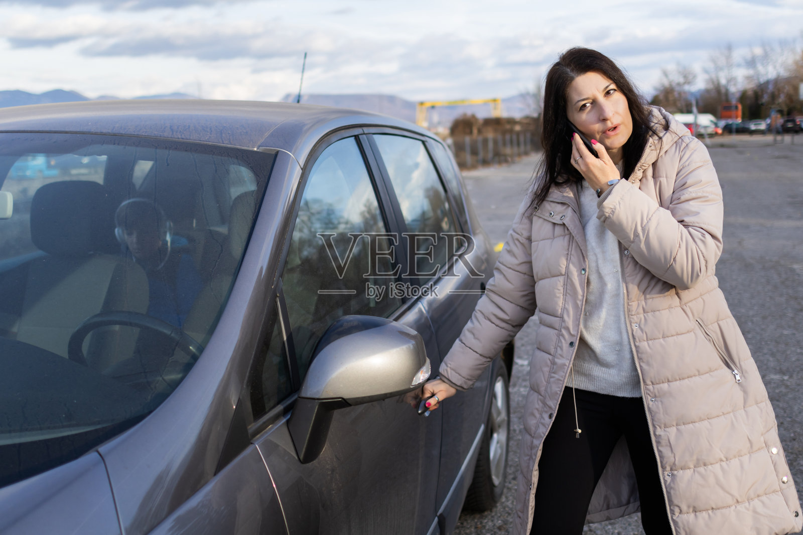 一位女士在开车途中停下来喝杯咖啡。她正在用手机打电话。照片摄影图片