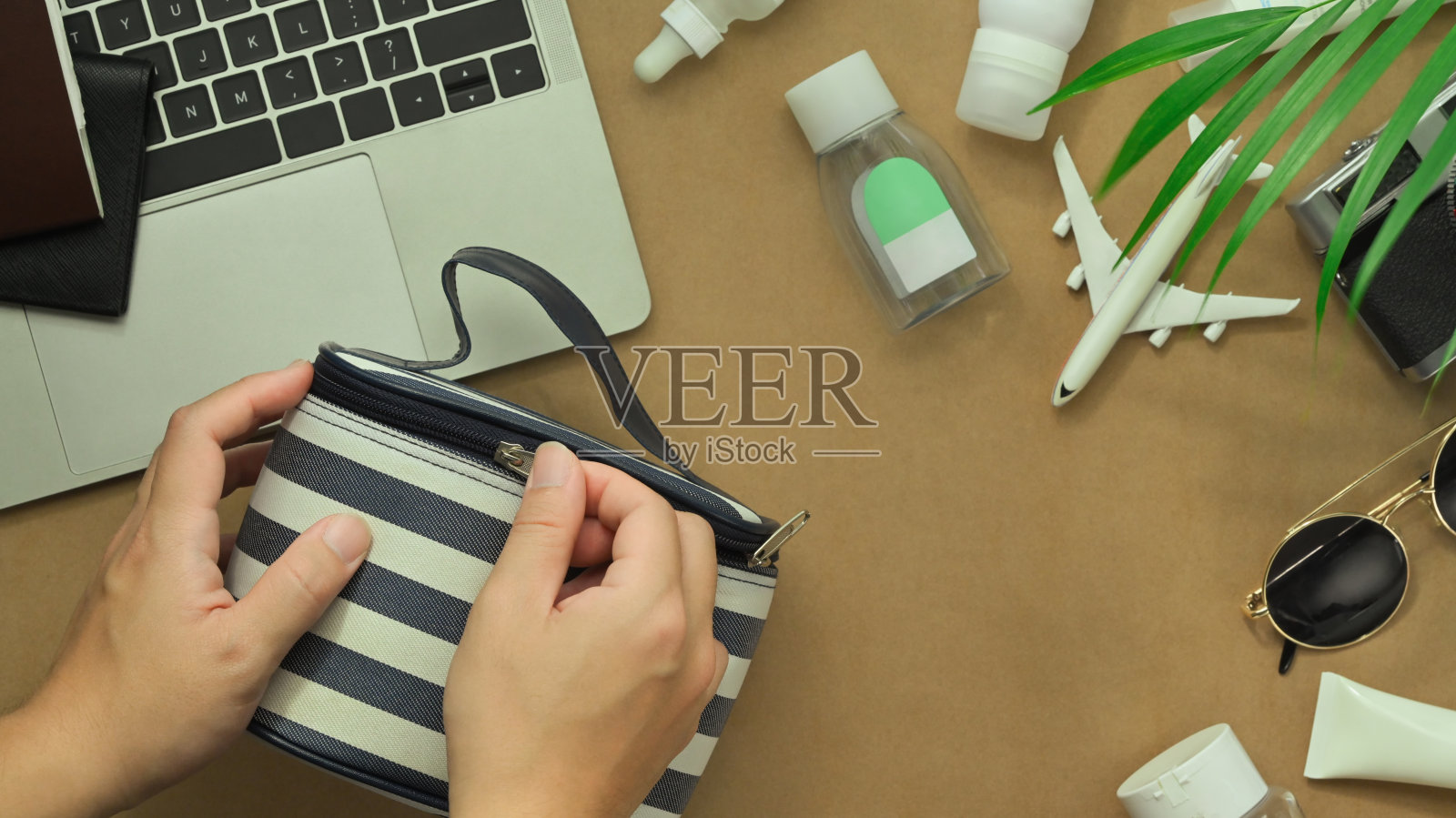 上图是男子在木桌上准备旅行化妆包。旅游度假理念照片摄影图片