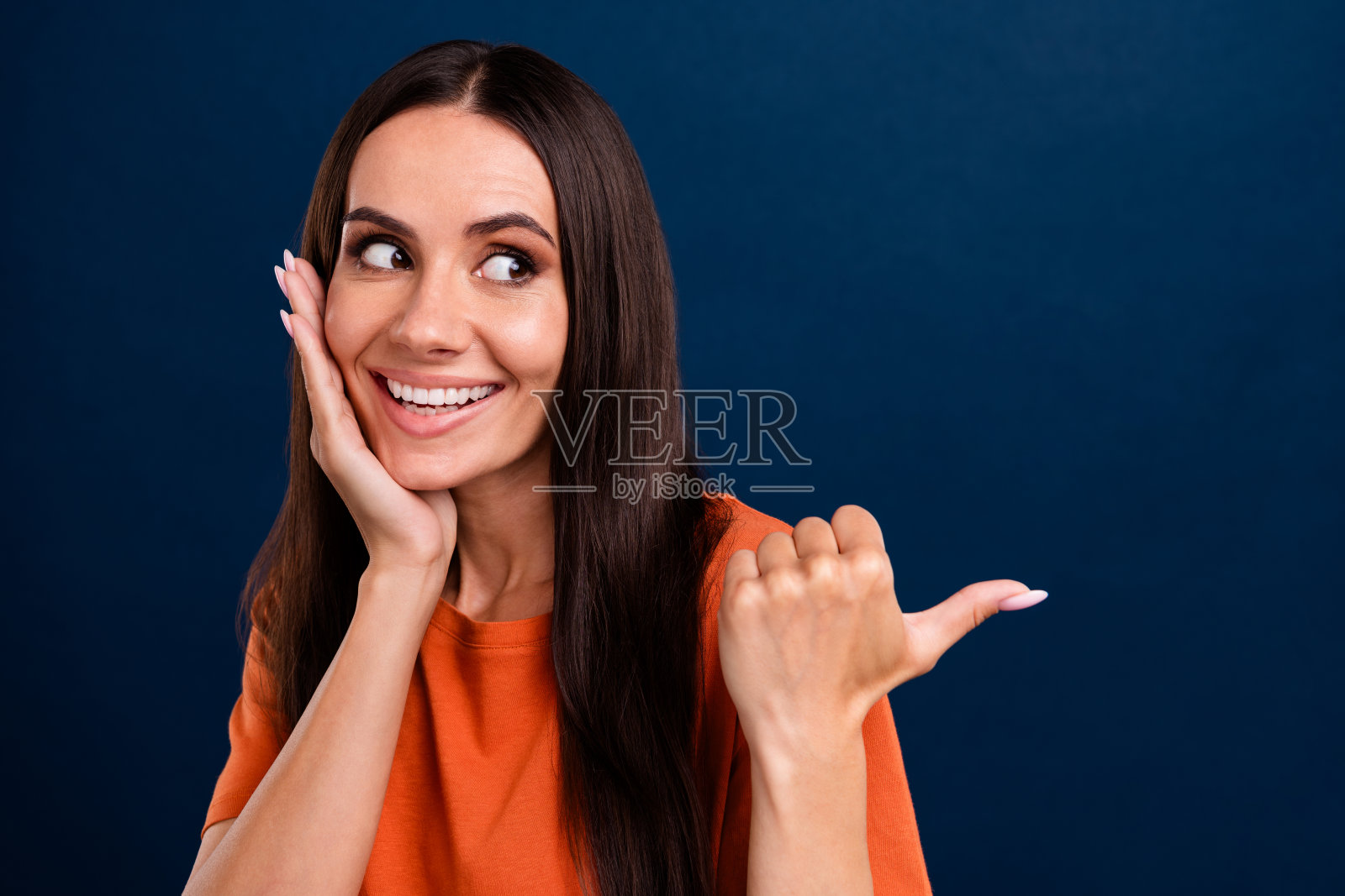 印象深刻的人的肖像穿着时髦的衣服,看着销售空白的手掌在颧骨上孤立在深蓝色的背景照片摄影图片