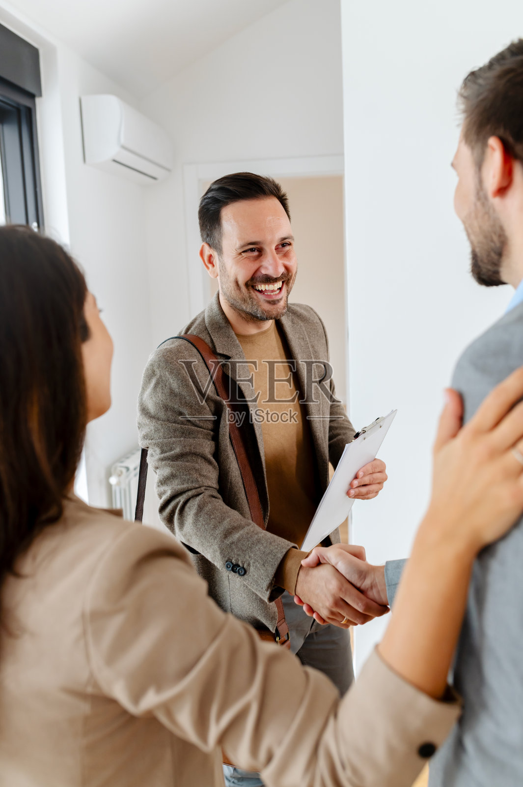 一对喜气洋洋的夫妇期待着孩子的到来,他们正在和正在参观待售或出租公寓的房地产经纪人交谈。照片摄影图片