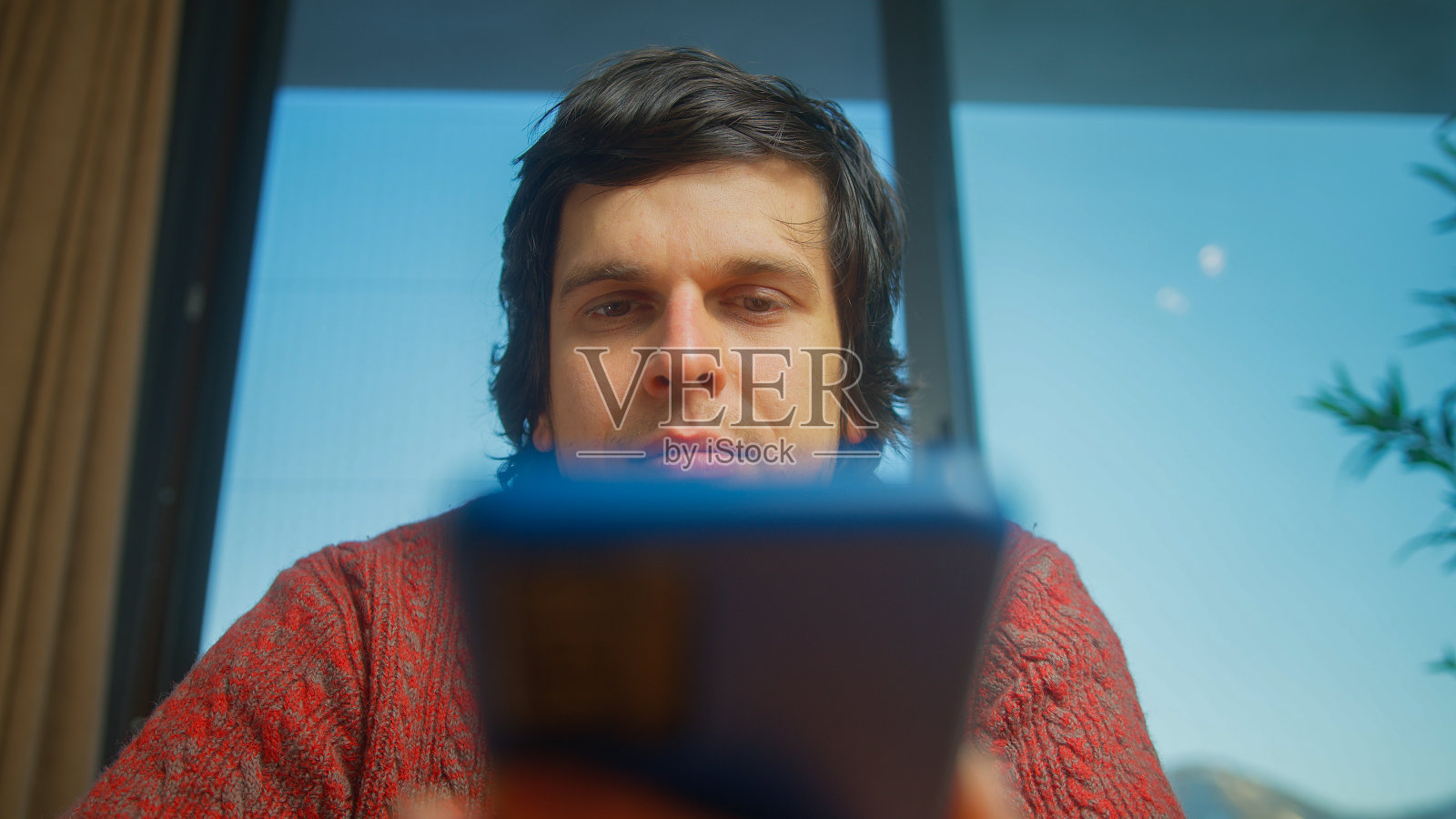 低角度拍摄的年轻人用手机上网,检查电子邮件,阅读媒体新闻,浏览社交网络,在家里使用智能手机上的移动应用程序照片摄影图片