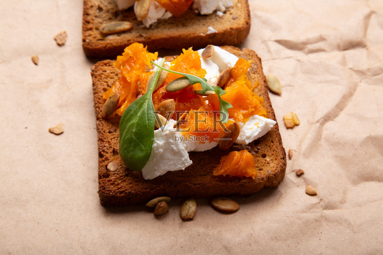 美味的烤南瓜吐司撒上种子和奶酪在谷物面包上。乡村的食物照片摄影图片