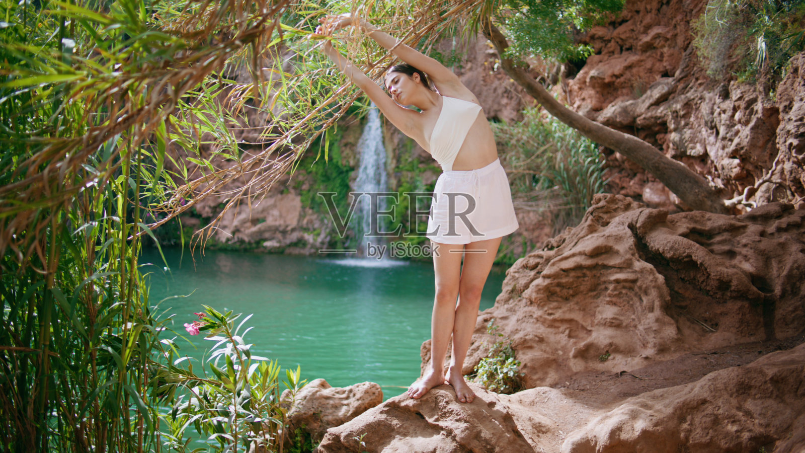 瑜伽女士在绿松石湖上做斜坡运动来暖身。赤脚女人伸展照片摄影图片