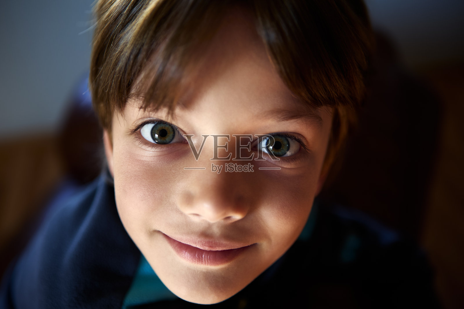 小男孩在阴凉的房间里睁大了眼睛。照片摄影图片