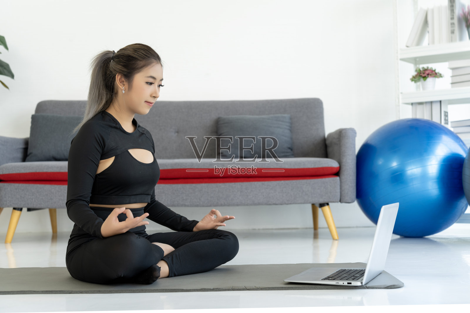亚洲女性在家练瑜伽,女性健身模特在笔记本电脑前冥想照片摄影图片