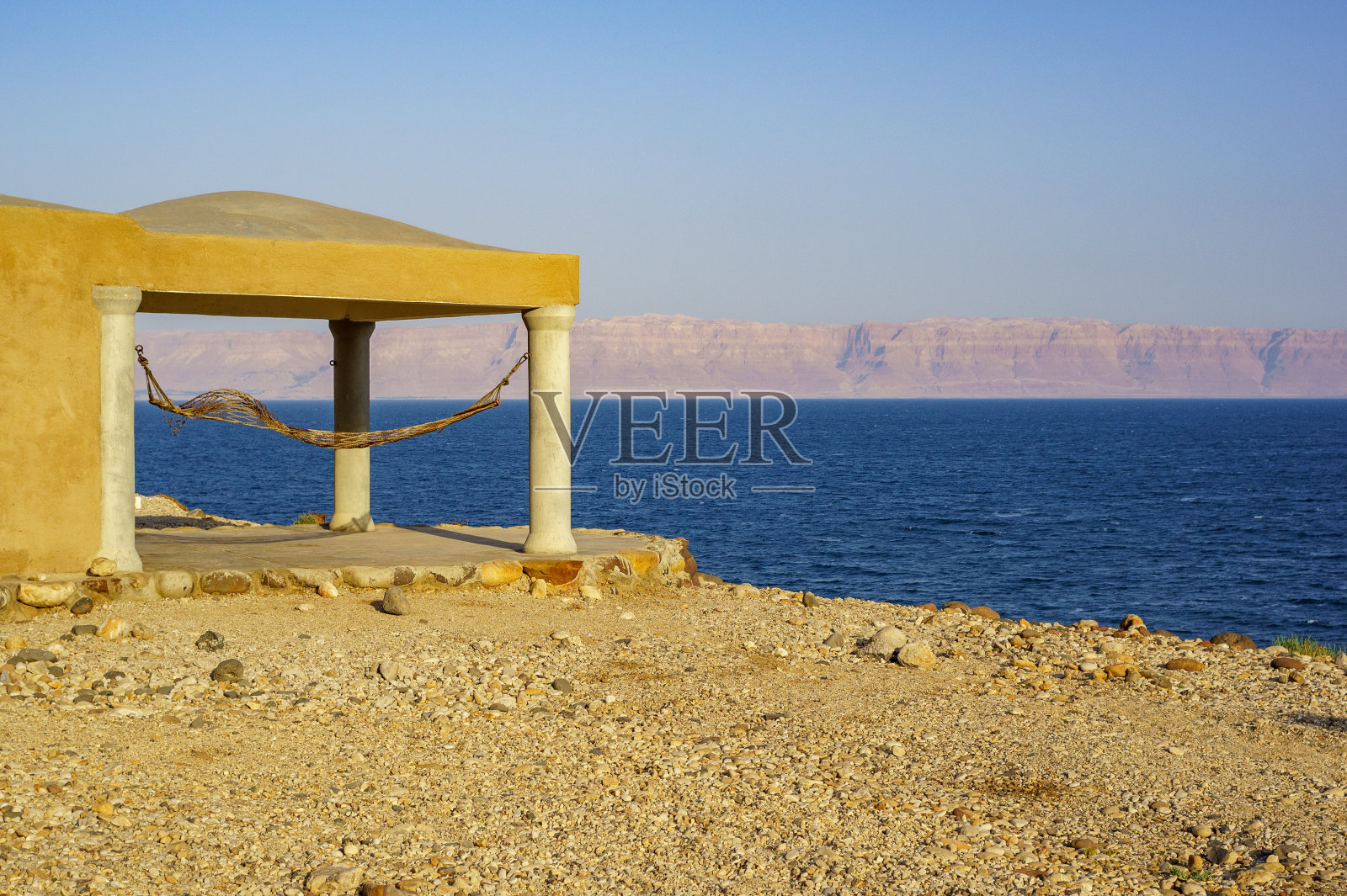 死海的岩石海岸。乔丹。死海的平静。死海碧绿的海水映衬着以色列海岸对面山脉的模糊背景。休息和治疗。照片摄影图片