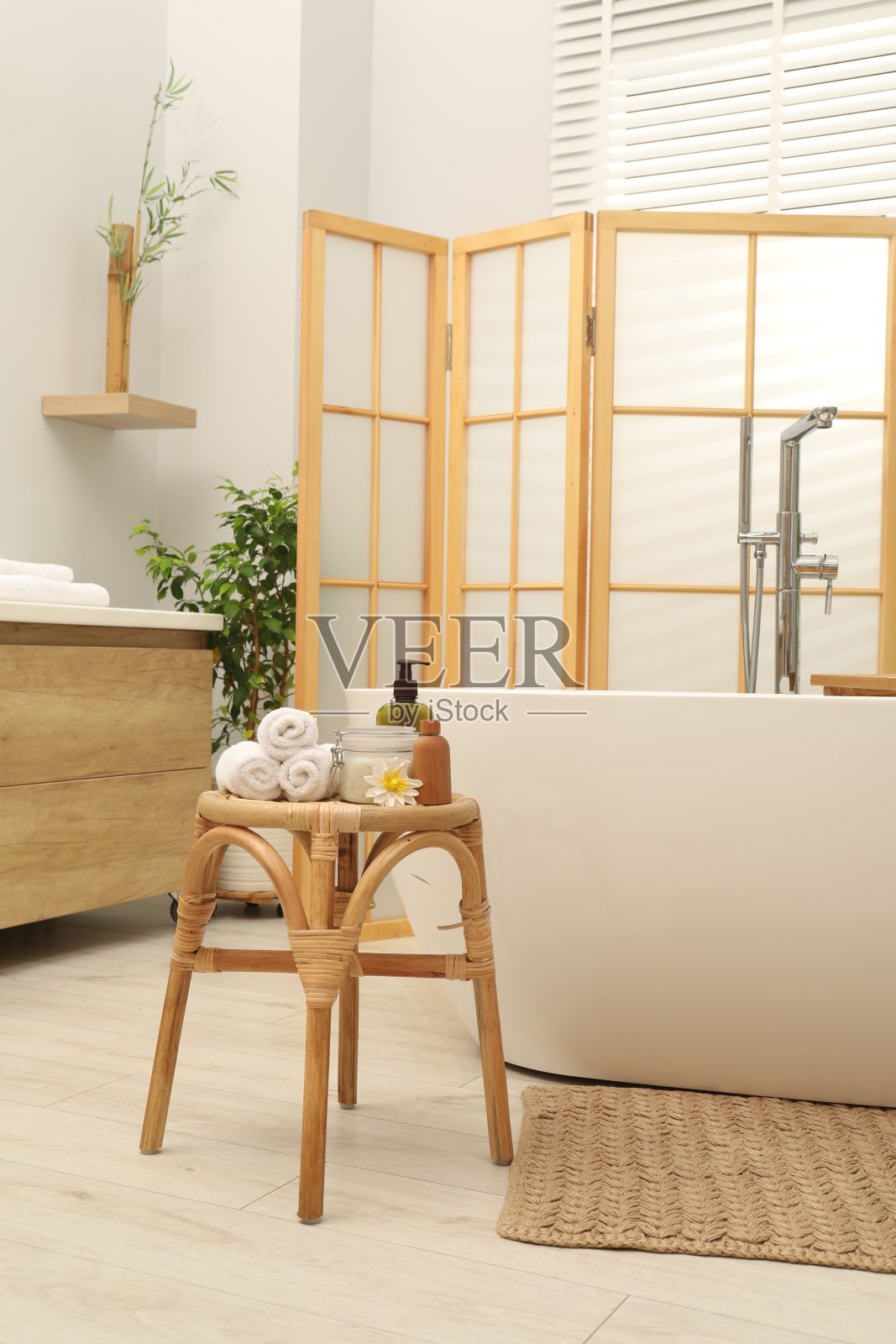 浴室里陶瓷浴缸旁边的柳条桌子上摆放着不同的水疗产品照片摄影图片