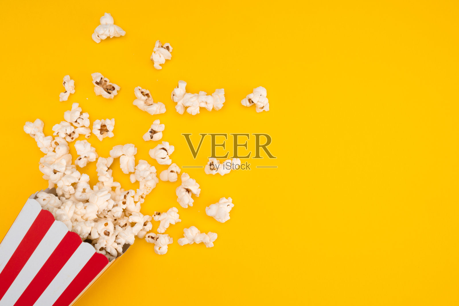 爆米花在红色和白色条纹纸盒孤立的黄色背景照片摄影图片